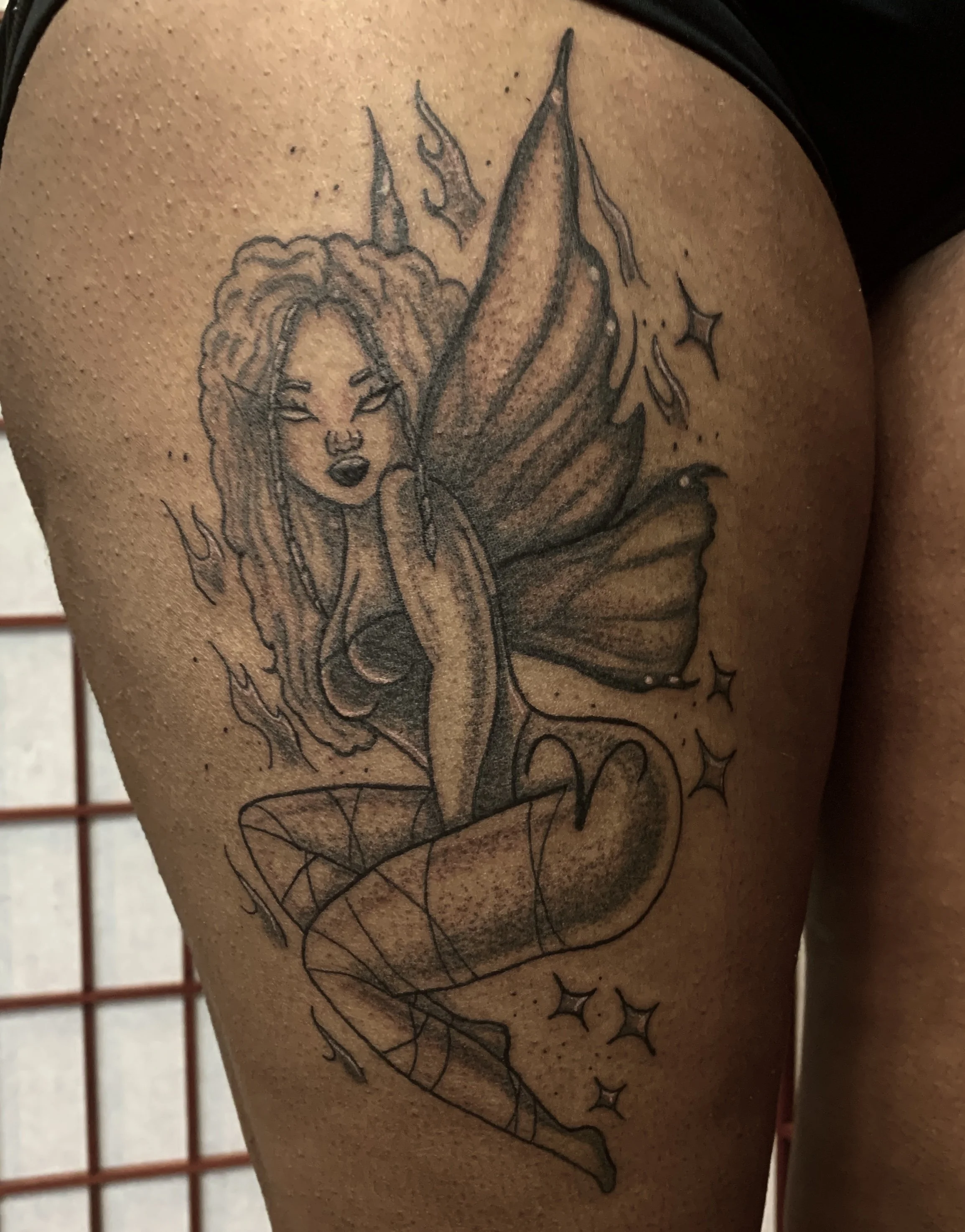 An illustrative, black and grey tattoo of a fairy.