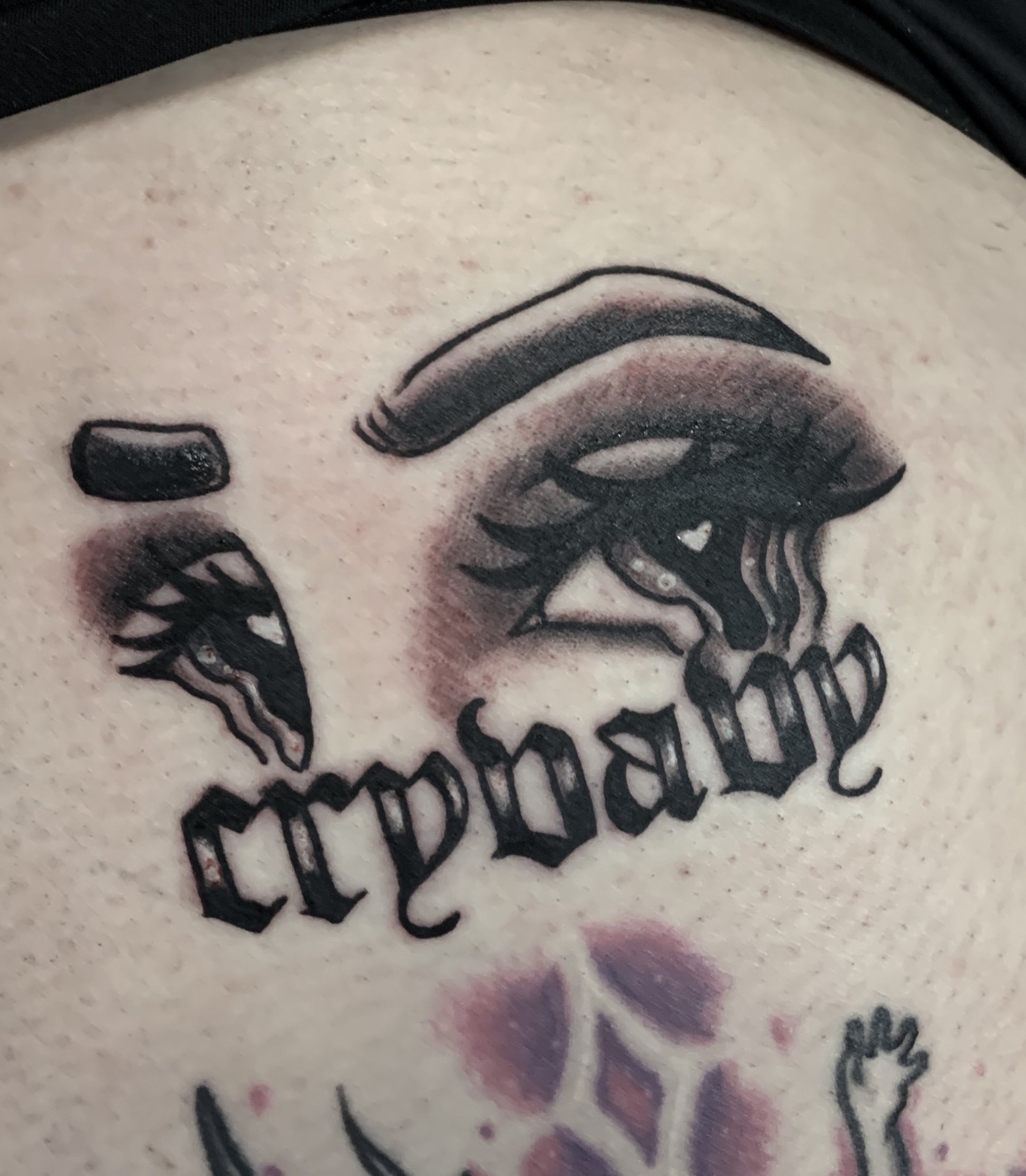 A black and grey "cry baby" eyes tattoo.