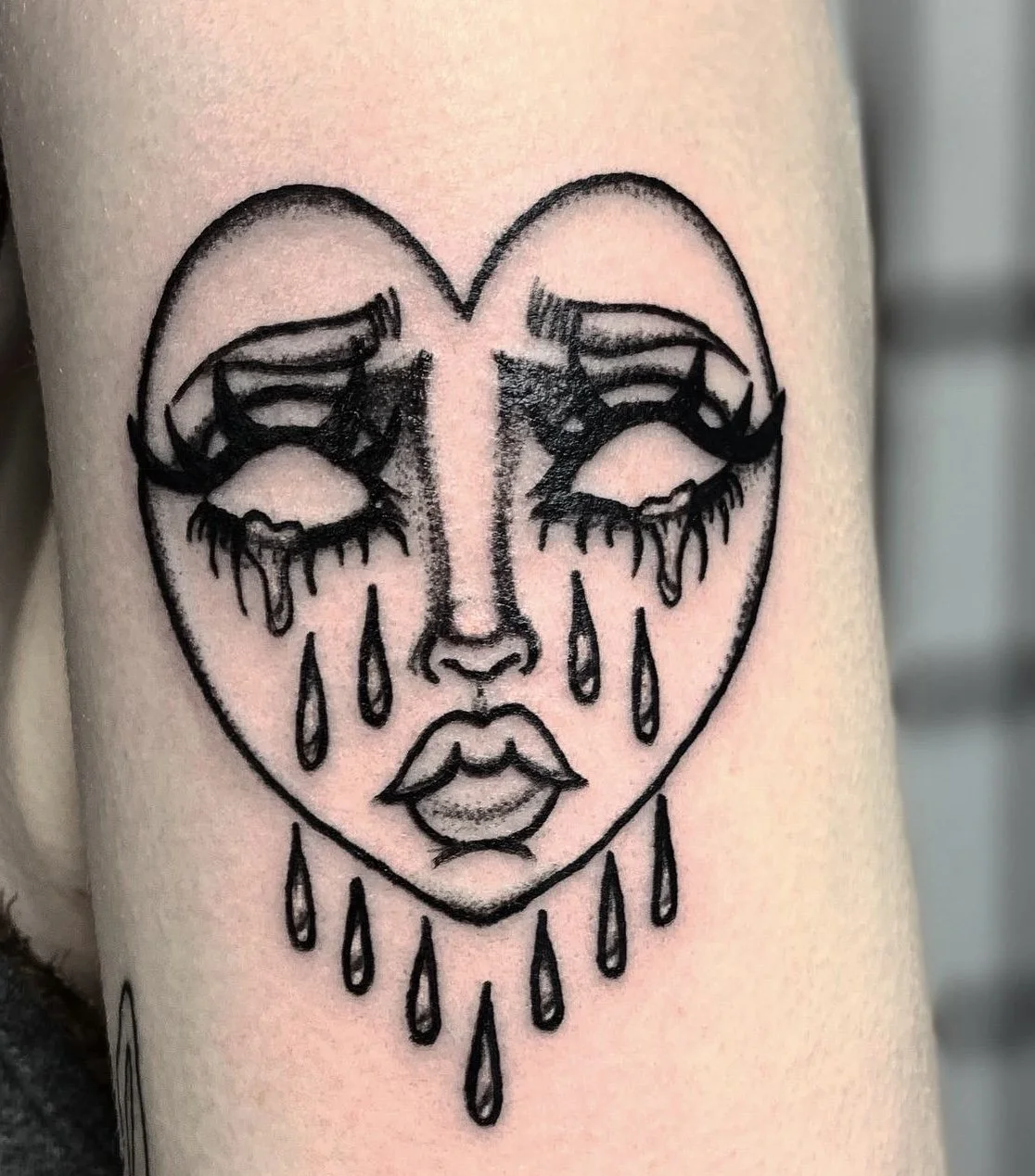 Crying gothic heart face tattoo.