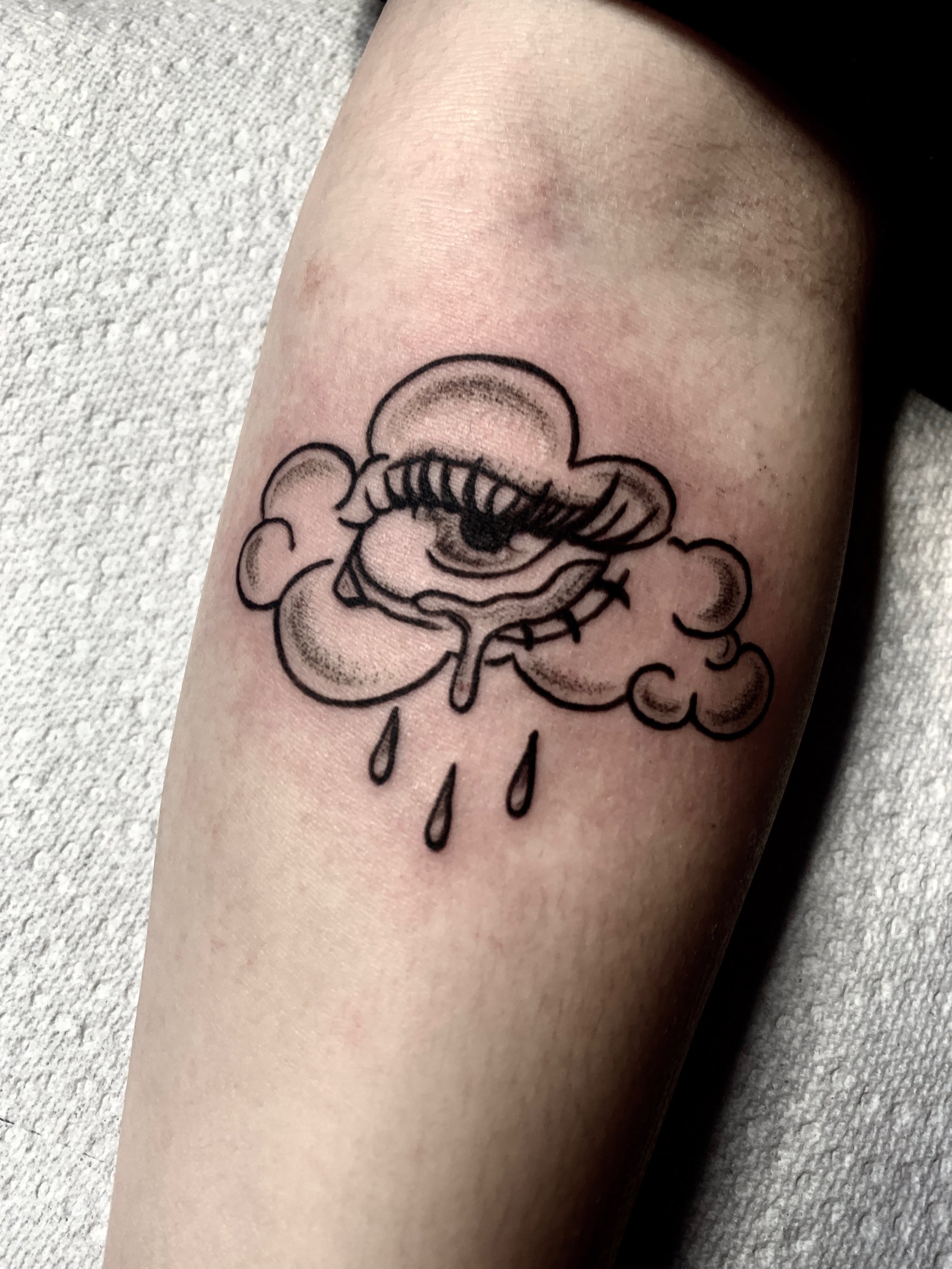 Crying eye cloud black and grey arm tattoo
