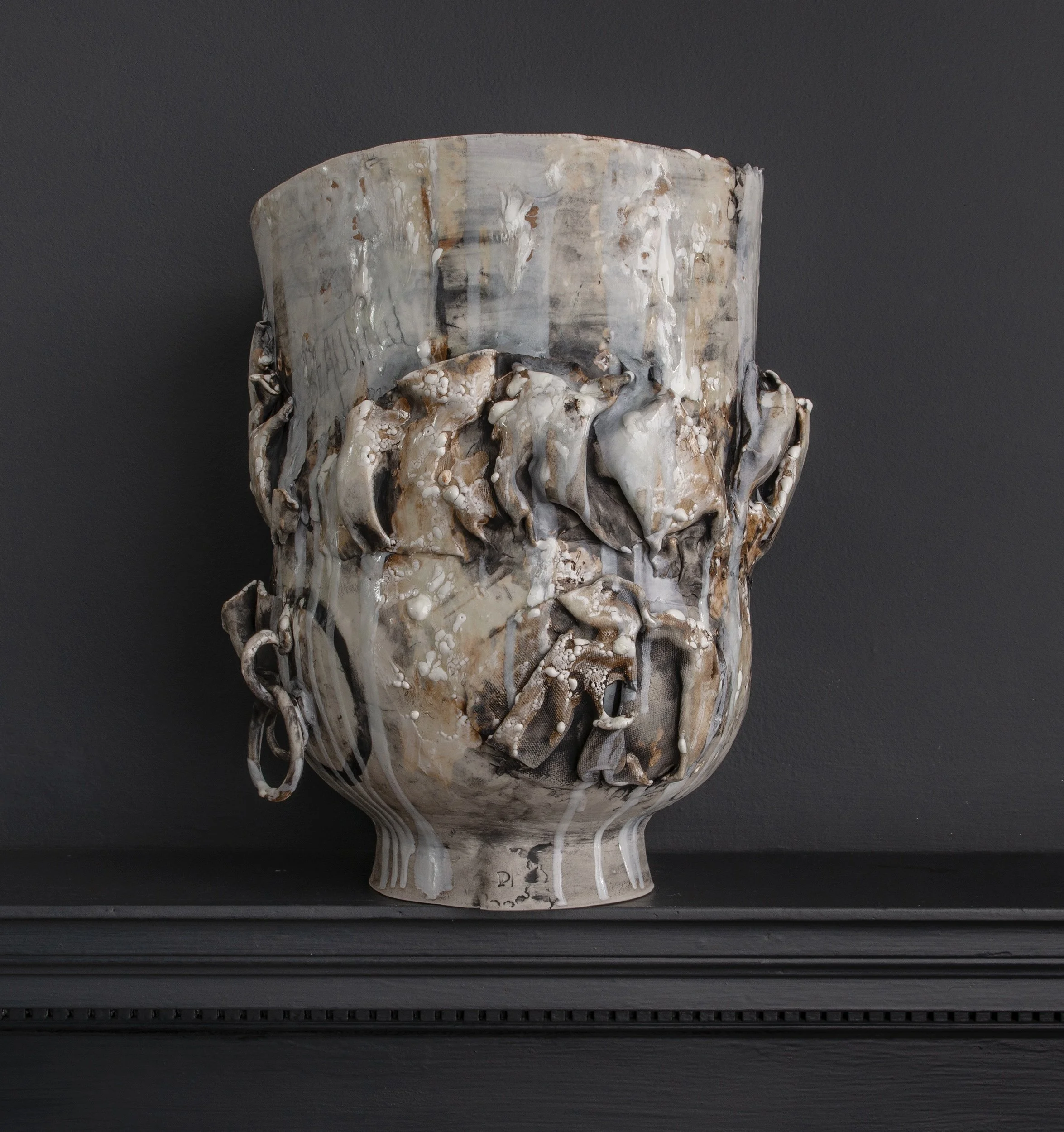 Close-up of a decorative glass vase with a marbled, textured surface in shades of beige, cream, and brown, against a dark background.