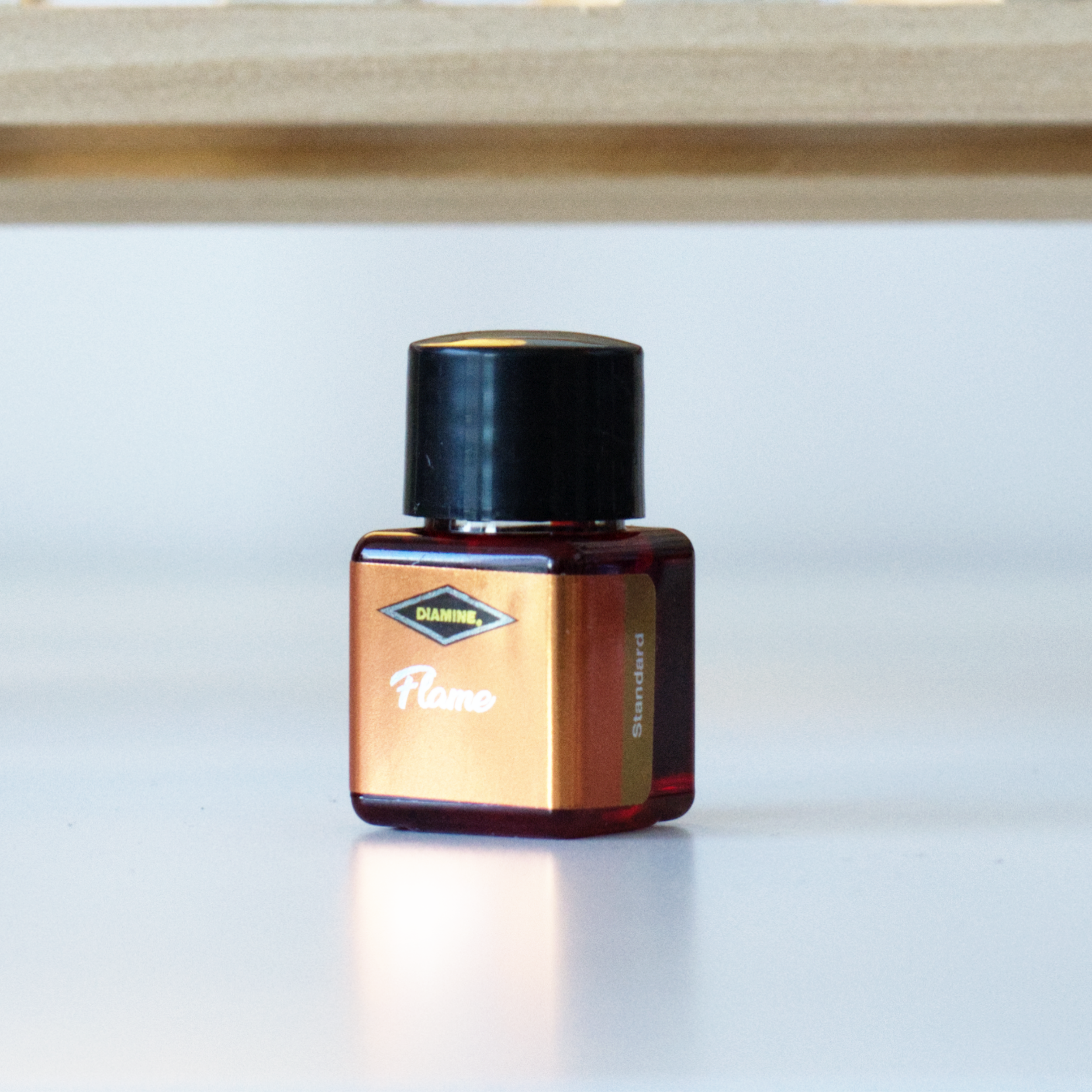 A photo of the 12mL bottle of Diamine fountain pen ink, in the colour Flame.