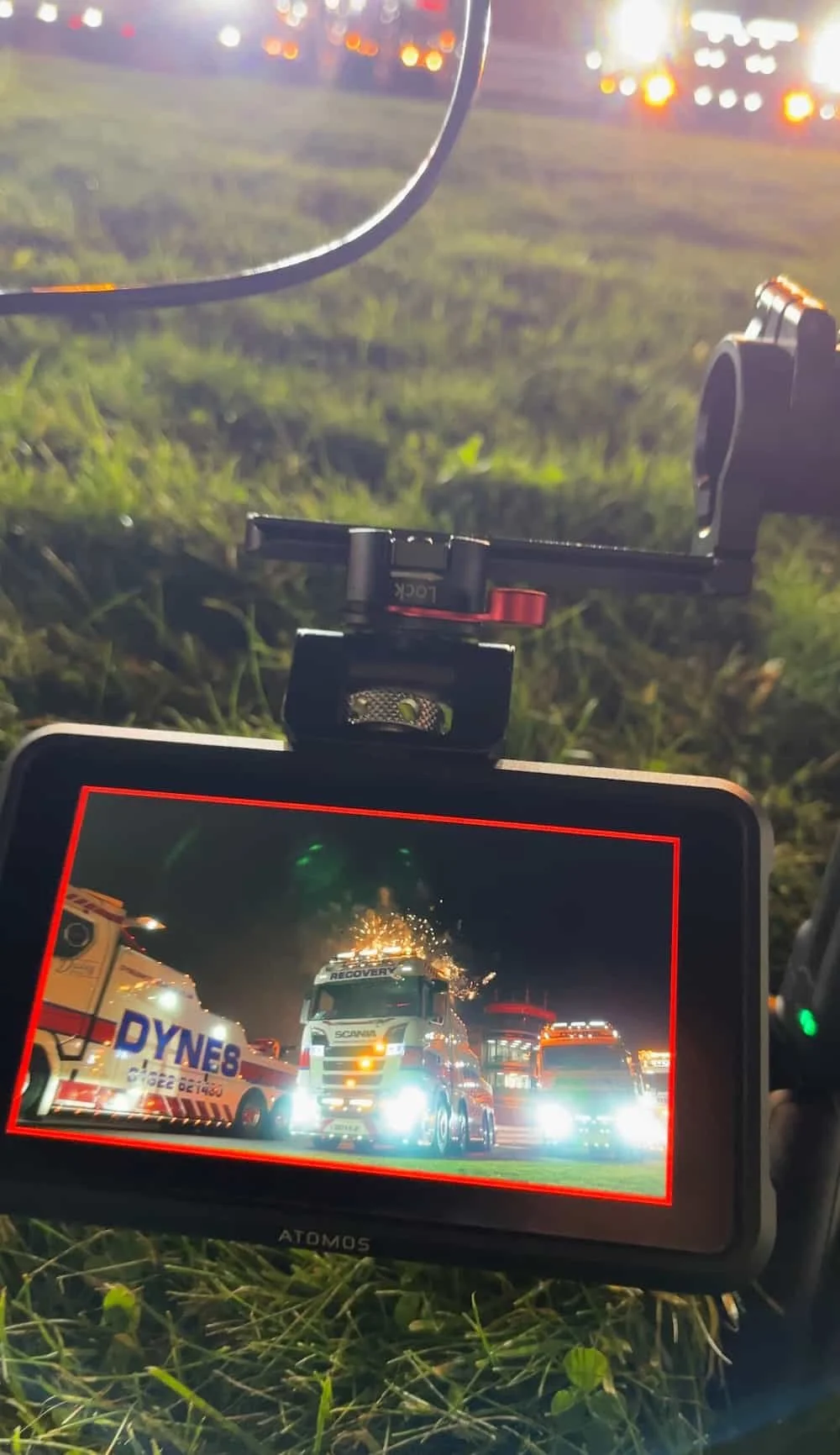 Behind the scenes photo of a video monitor showing a Dynes Motor Group recovery truck framed against fireworks at Brands Hatch during a live event shoot