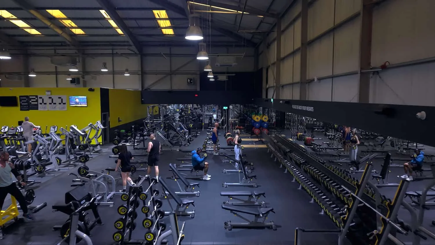 Inside a spacious gym with various workout equipment and people exercising.