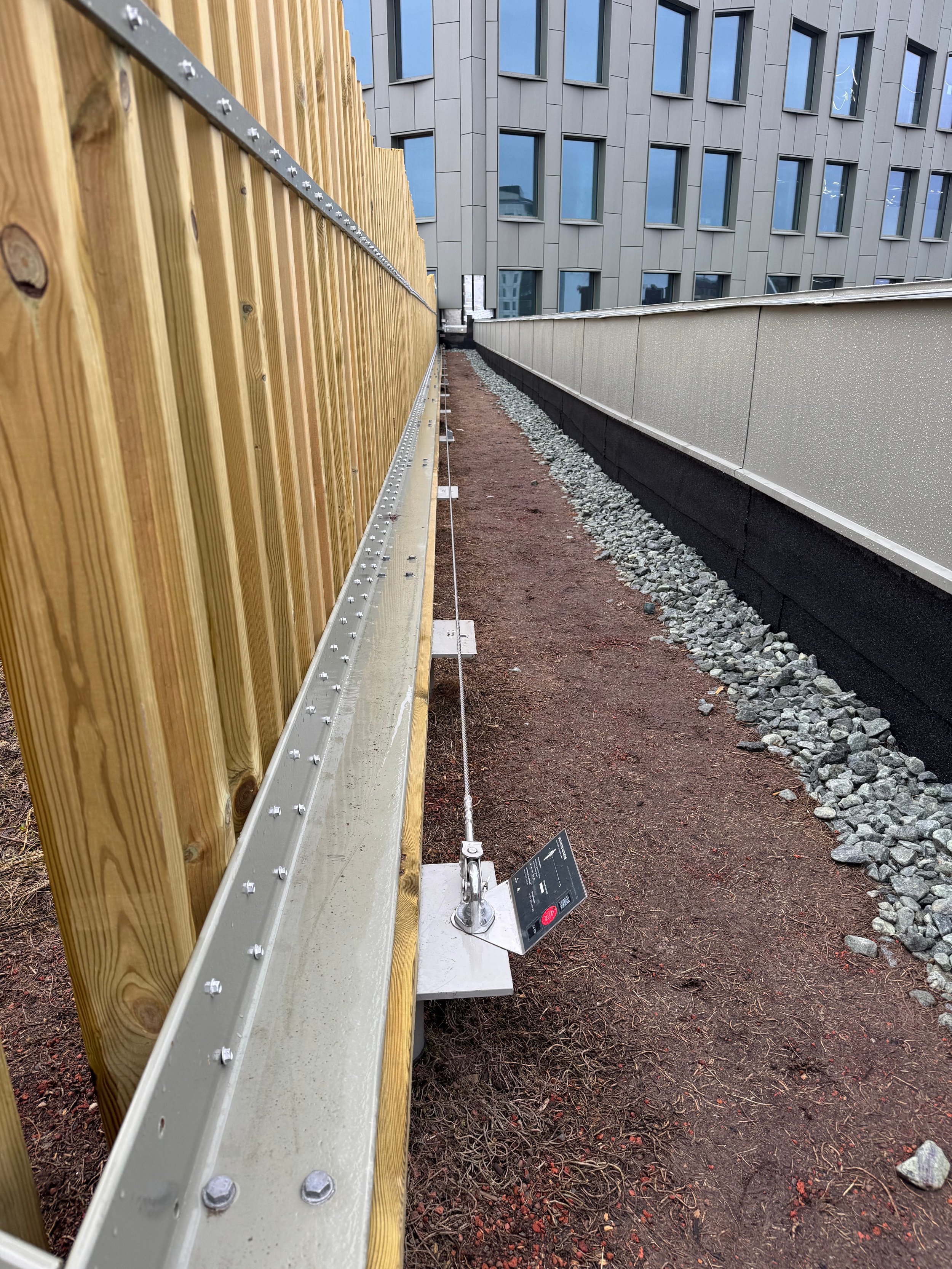 A fence mounted fall protection and rope access wire on the roof top terrace of Olivin, Stockholm.