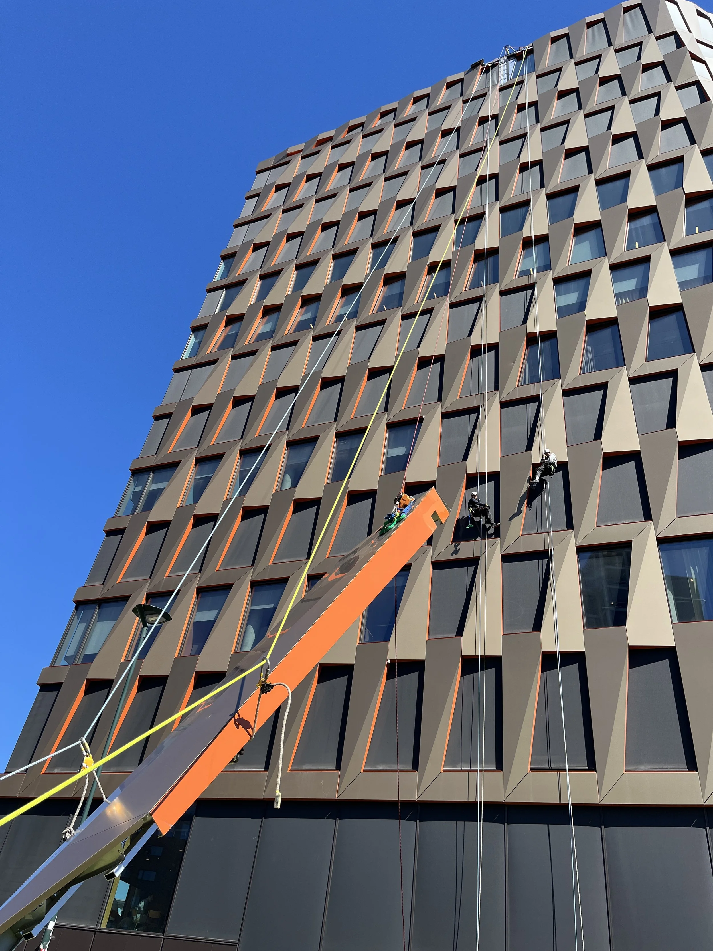 Høyden climbers installing a facade element from ropes on Valle Vision, Oslo