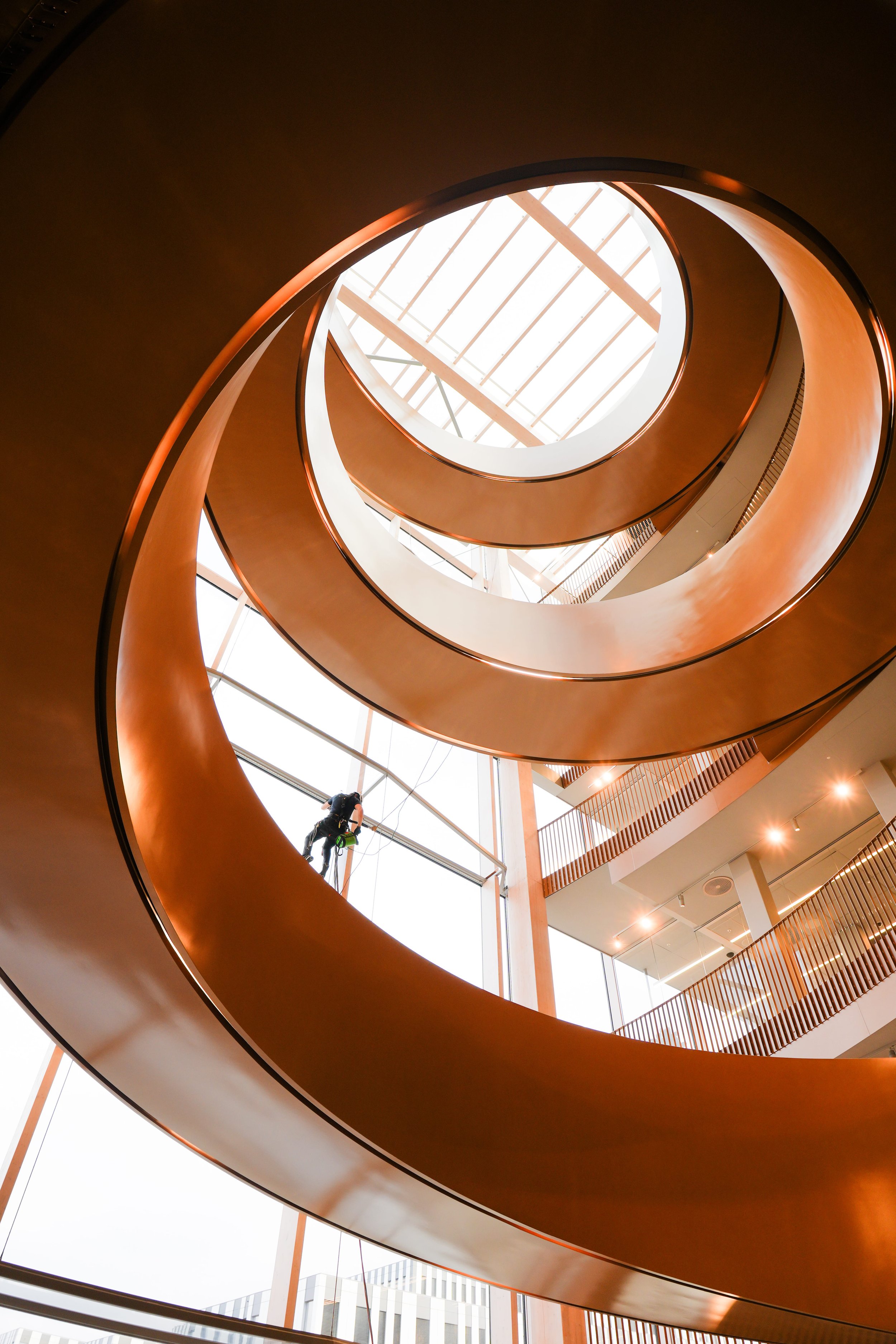 Høyden climber on the facade of a building with a round golden staircase behind him.jpg