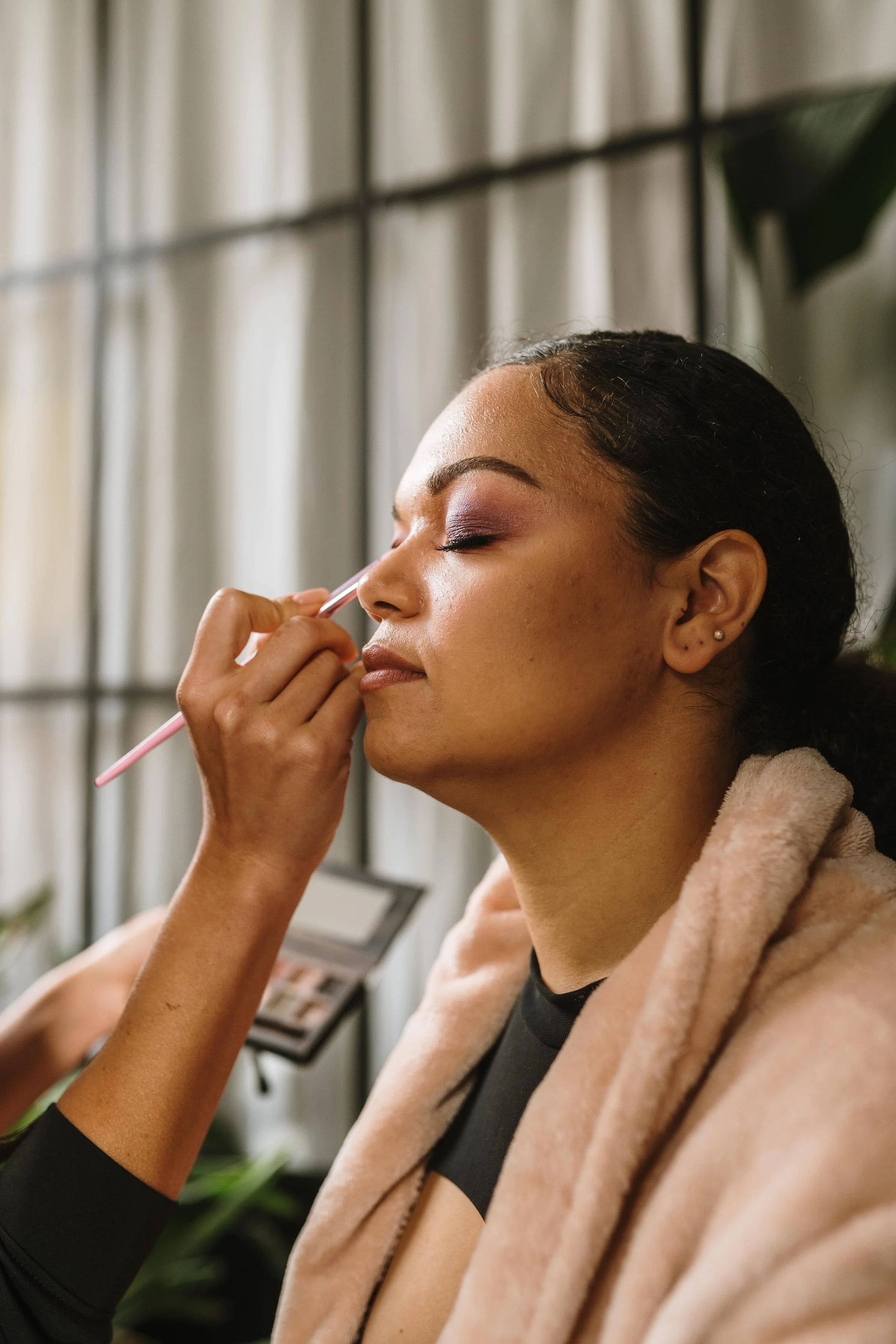 Afroamerikanische Frau, die sich ihr Make-up von einem Make-up-Artist auftragen lässt
