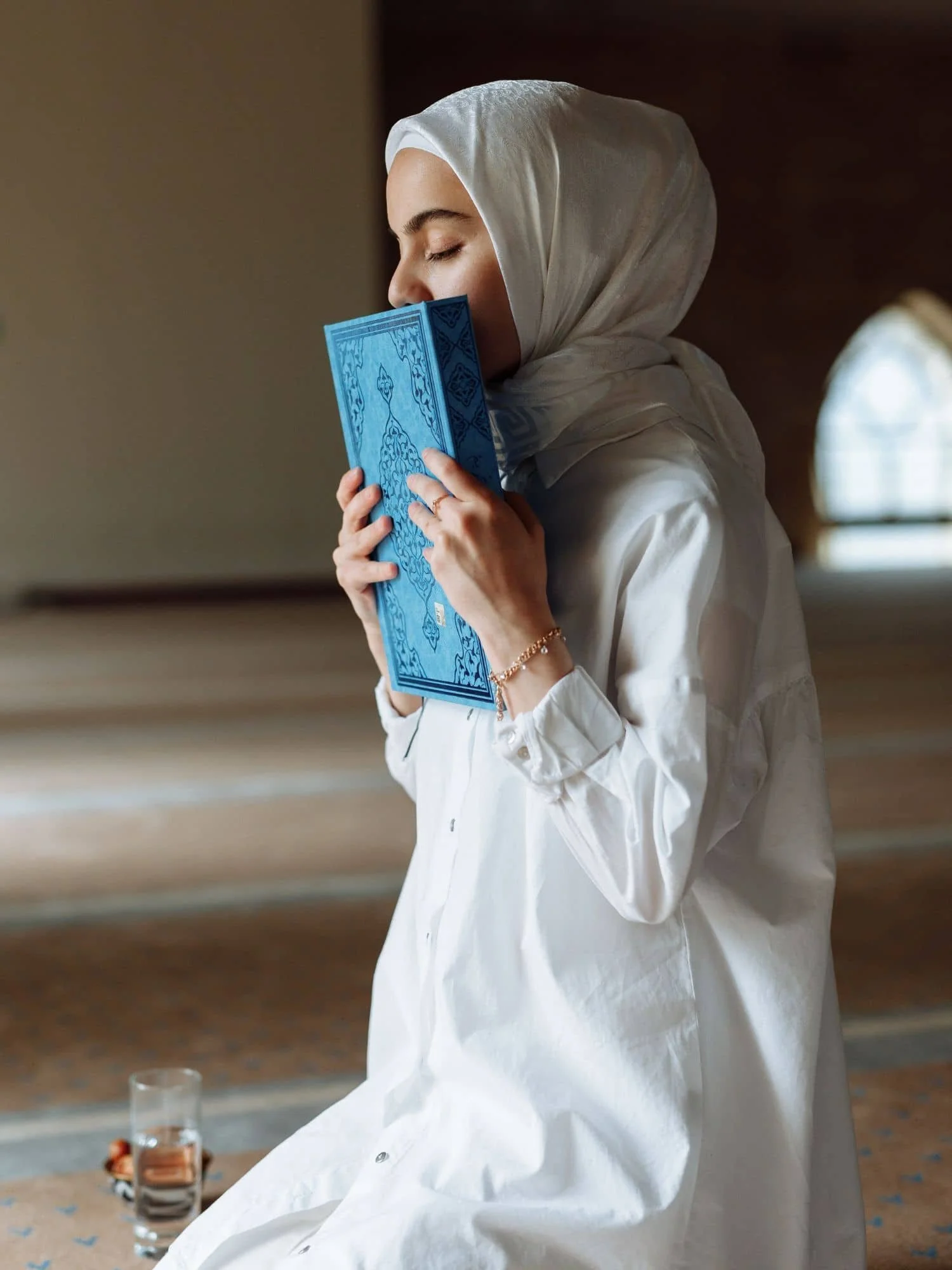 Femme musulmane qui prie dans une mosquée coran à la main