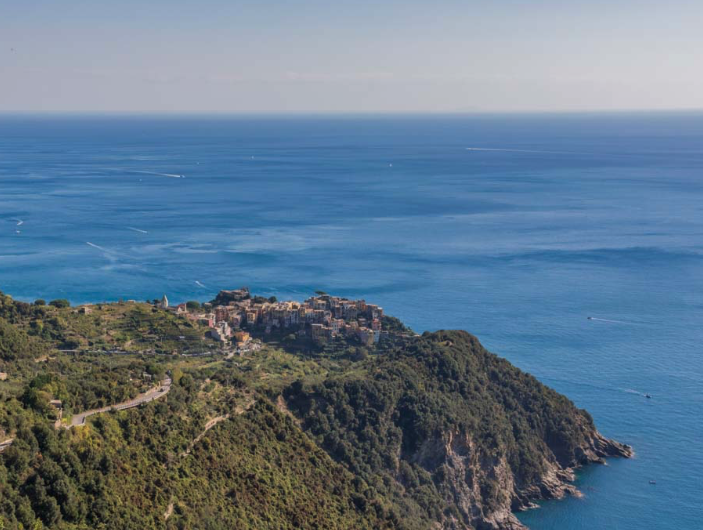 Corniglia with coastal town on a hillside overlooking the ocean with boats visible on the water.