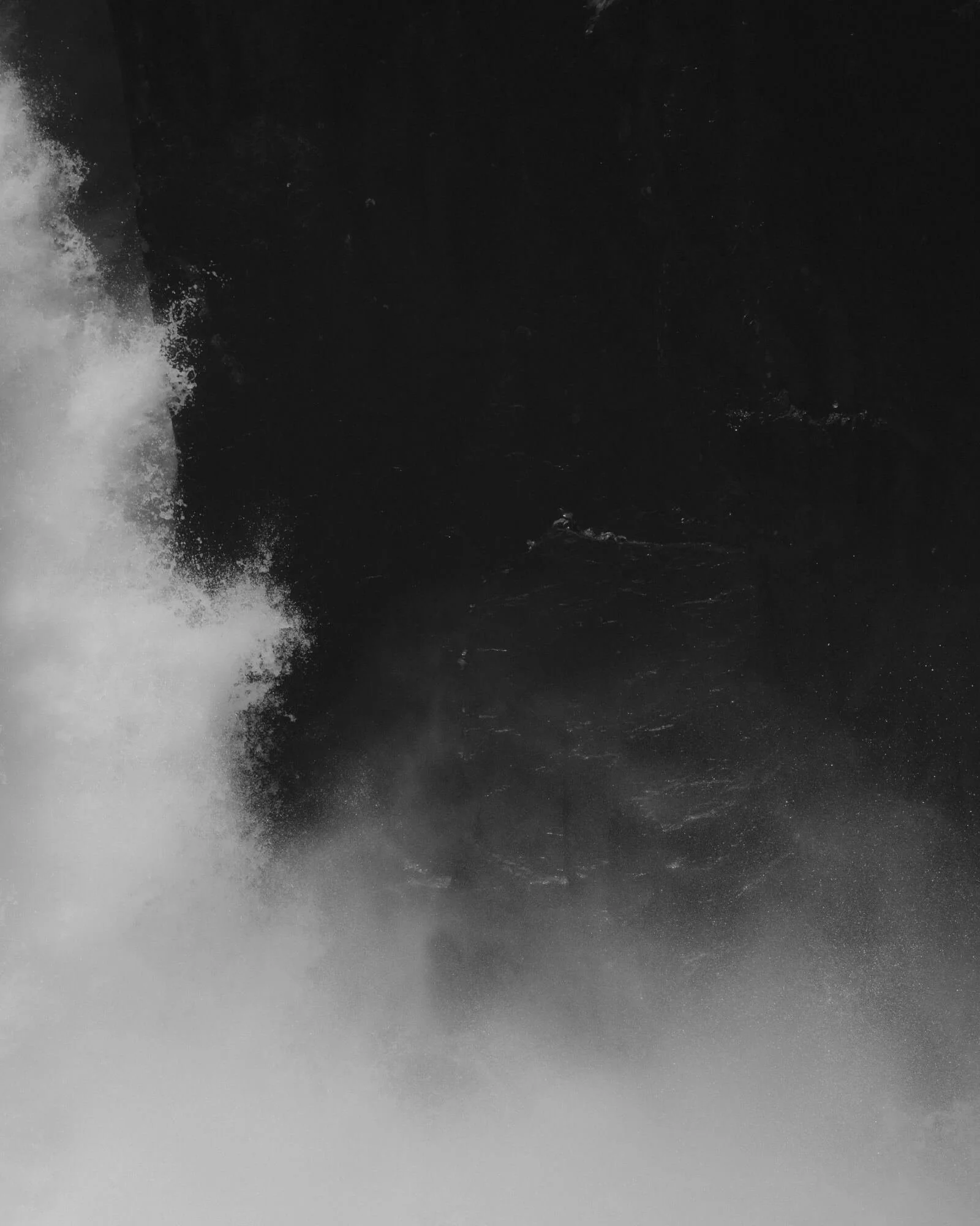 A monochrome abstract image with a horizontal gradient dark to light, featuring a textured splash of white on the left side.