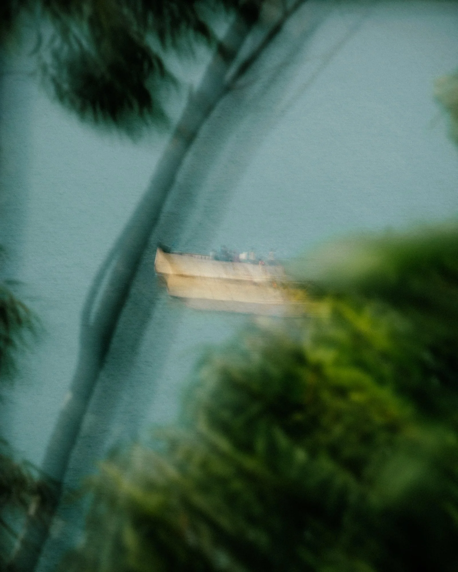 A blurry indoor scene with a blue painted wall, a staircase, a wooden or cardboard box, some greenery, and a window or wall opening.