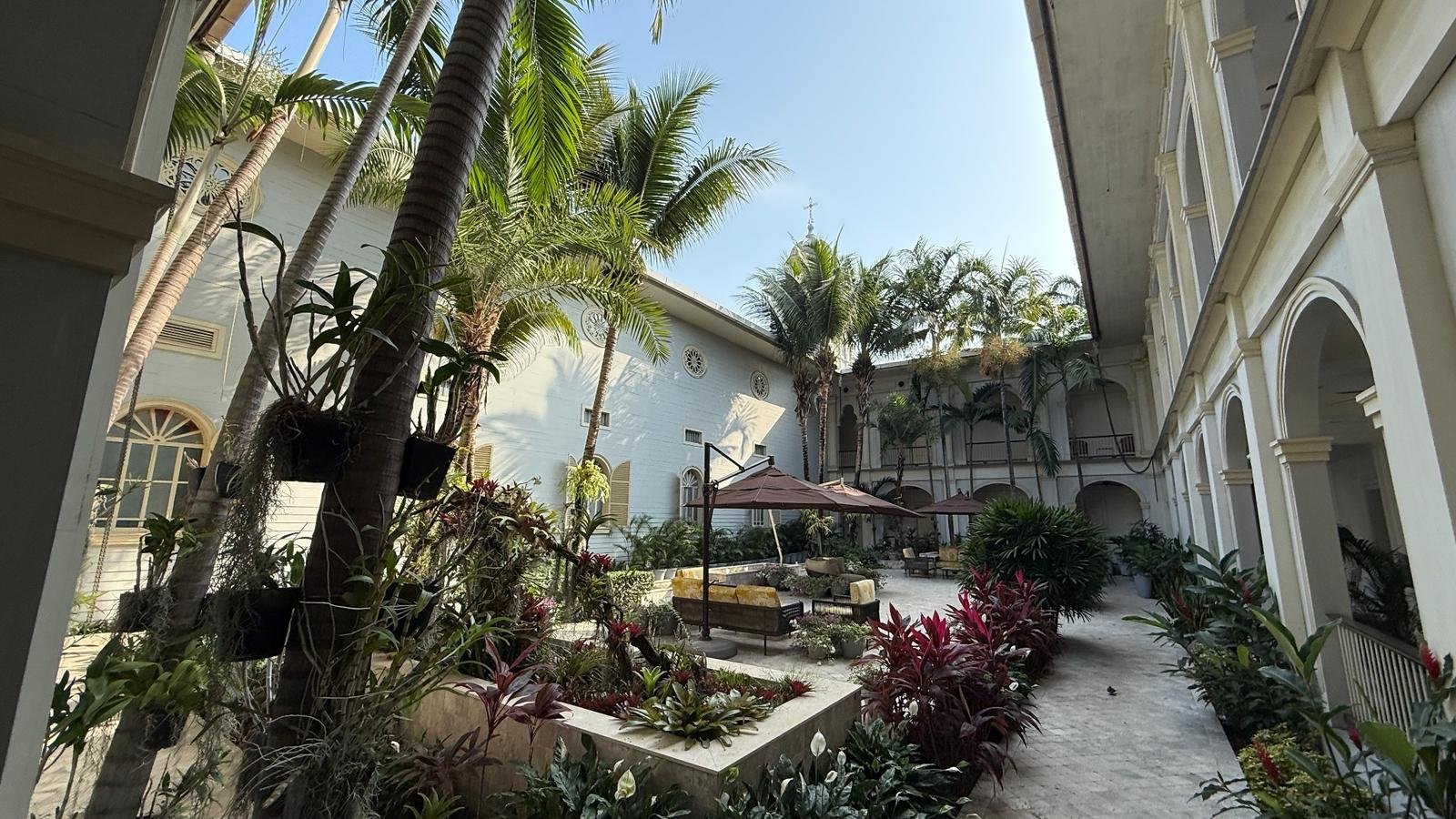 Lush tropical courtyard with palms, seating and white colonial architecture at a historic Guayaquil hotel