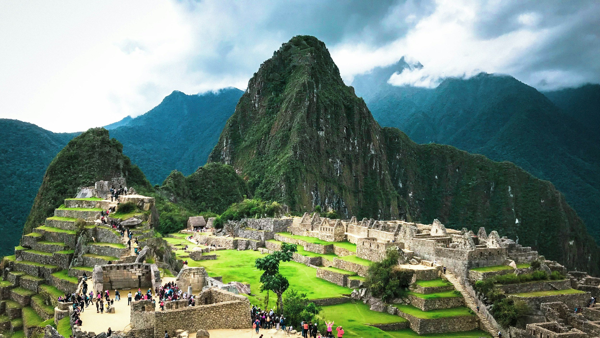 Machu Picchu mountain with ruins in front and dark cloudy sky