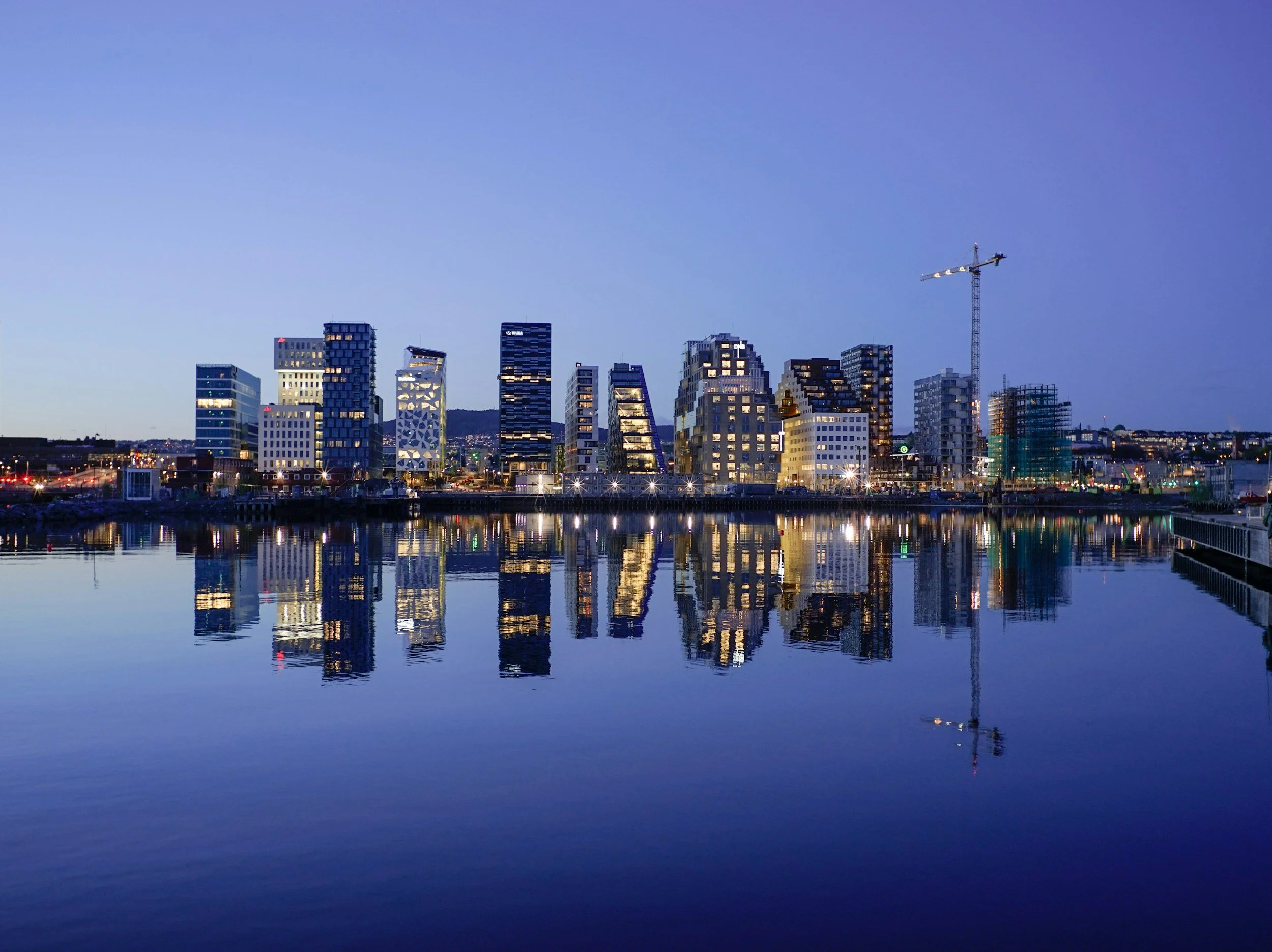 Night view of Oslo’s Barcode Project skyline with modern architecture reflected in the Oslofjord water