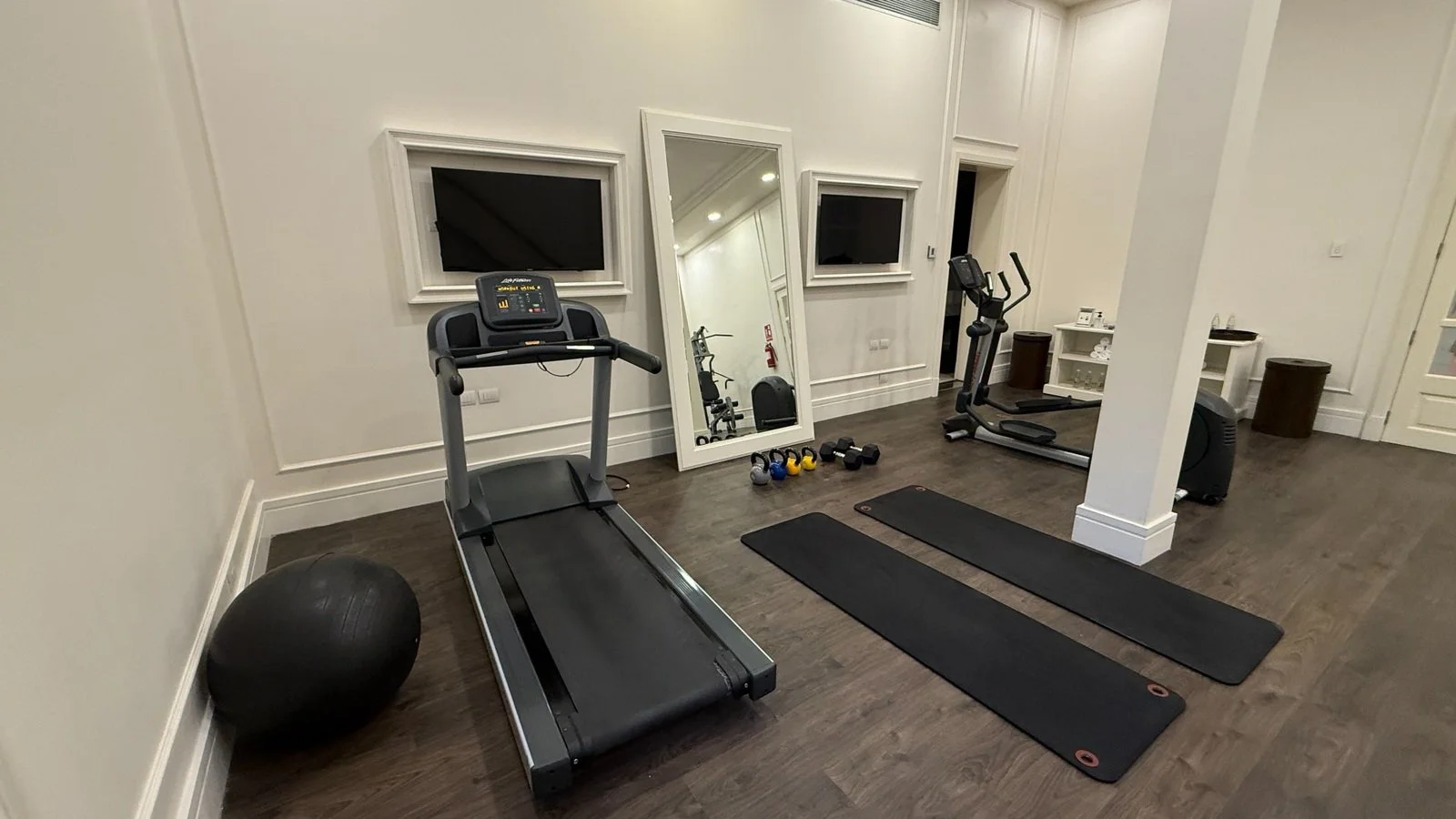 Private luxury hotel gym with treadmill, yoga mats, free weights and fitness equipment in an elegant boutique hotel setting