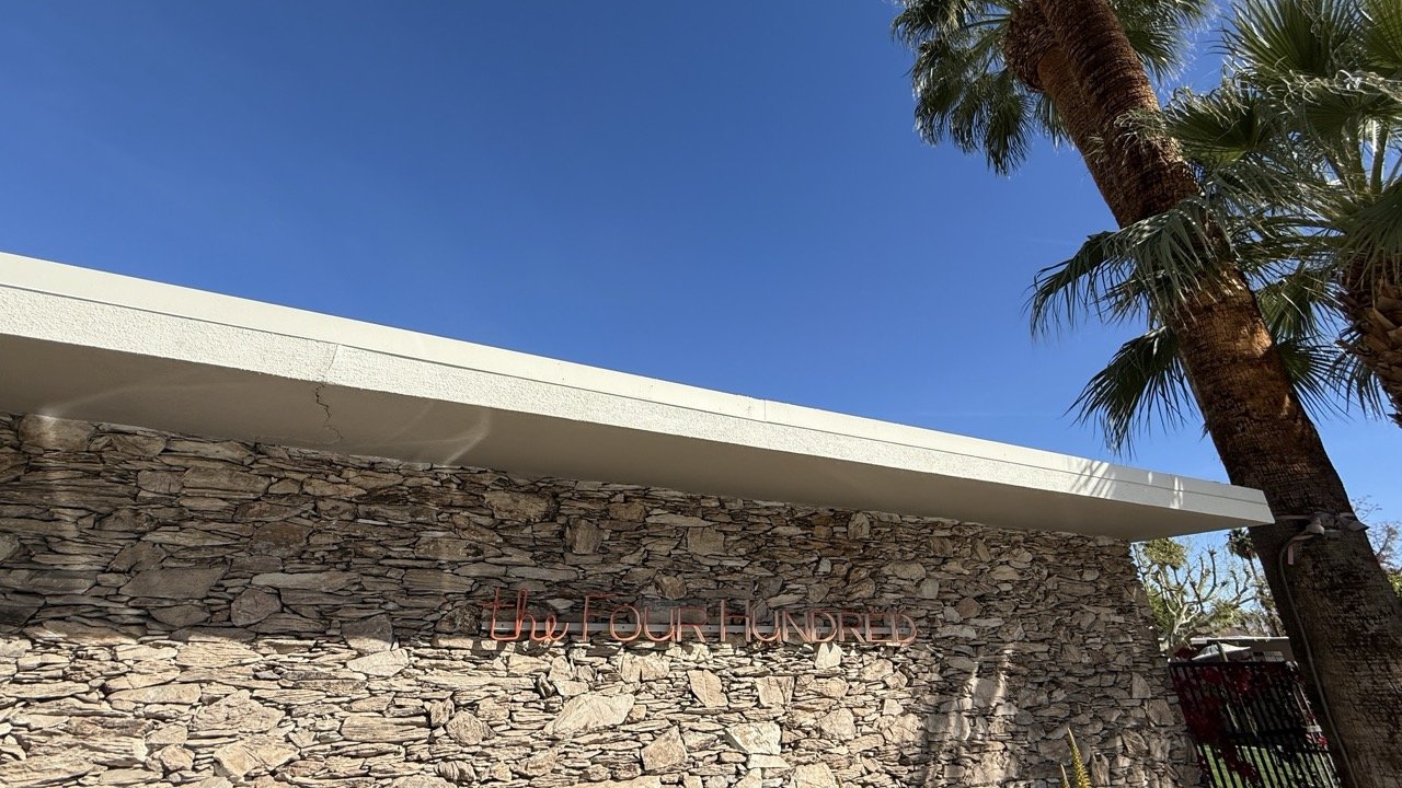 The Four Hundred building in Palm Springs, featuring a stone facade with mid-century modern architectural details under a clear blue sky.