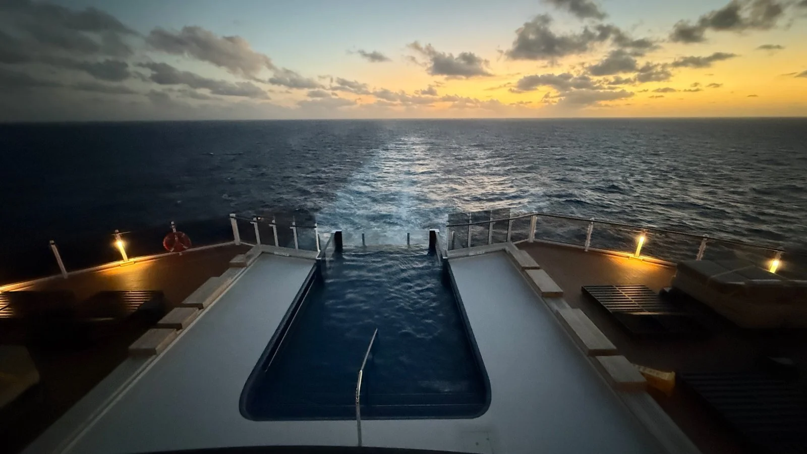 Infinity pool at the rear of a cruise ship at sunset overlooking the open ocean with warm evening light