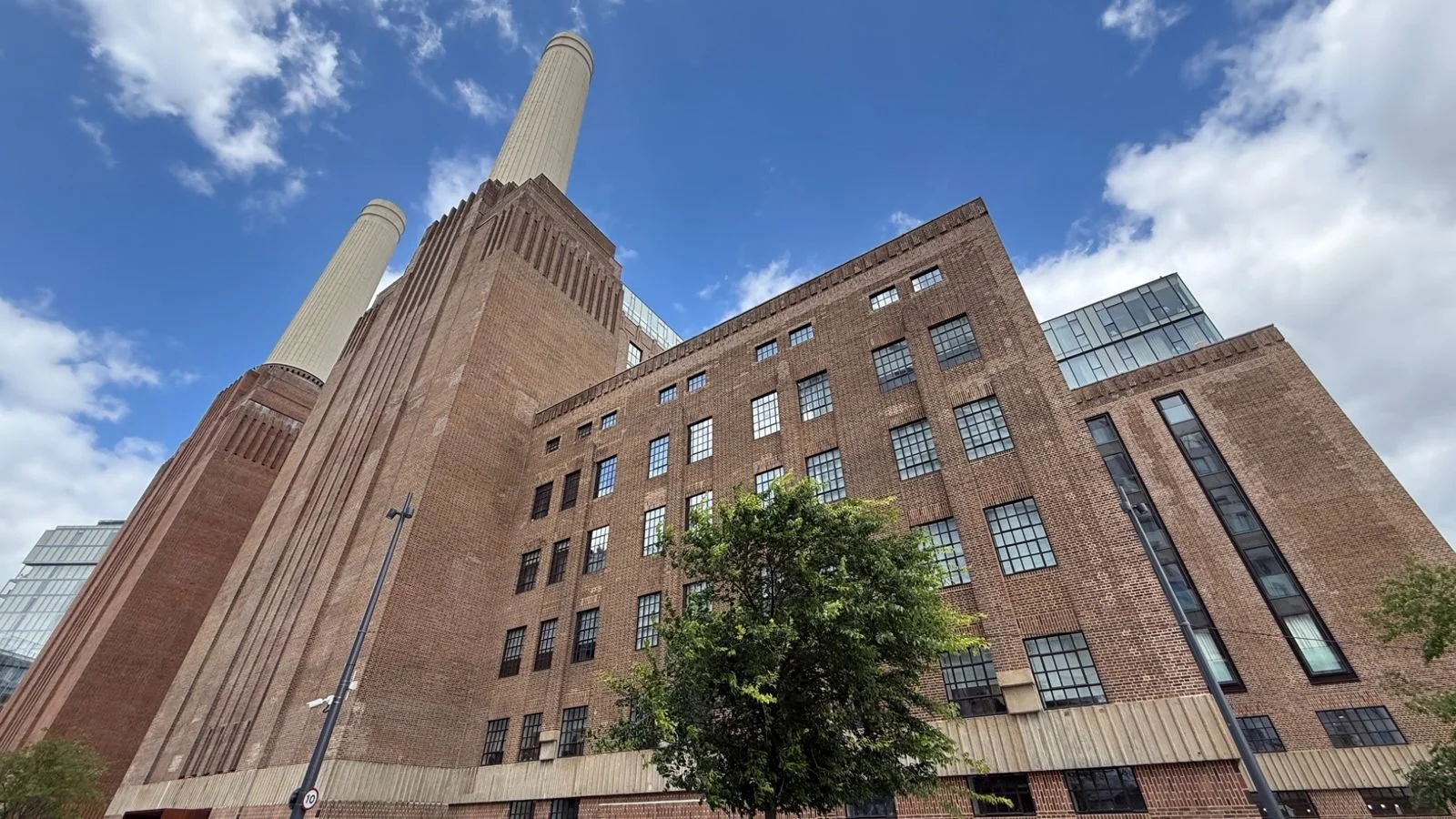 Exterior view of Battersea Power Station in London with its iconic brick façade and chimney towers under a blue sky