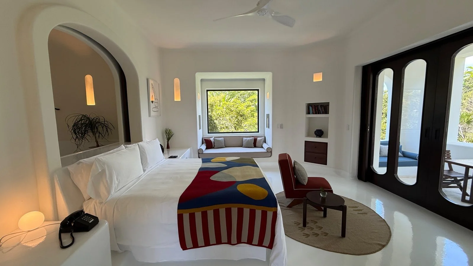 Spacious Hotel Esencia suite with modern design, king bed, seating area and views of tropical greenery