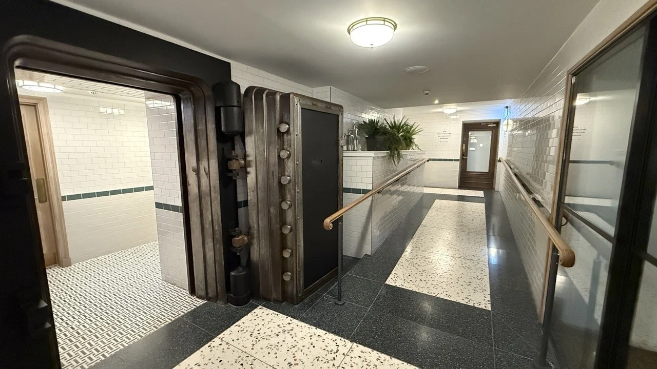 A historic vault-style door leading into the tiled hallway of The Strong Rooms, preserving the building’s original character.
