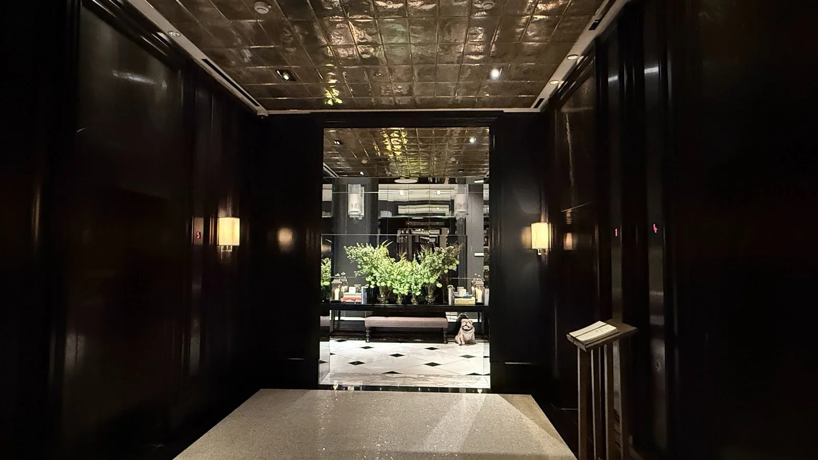 Dark wood lift lobby with floral display at Rosewood London