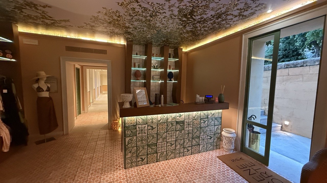 Reception area of the spa at Villa Igiea in Palermo, featuring hand-painted Sicilian tiles, a botanical ceiling design, and soft ambient lighting.