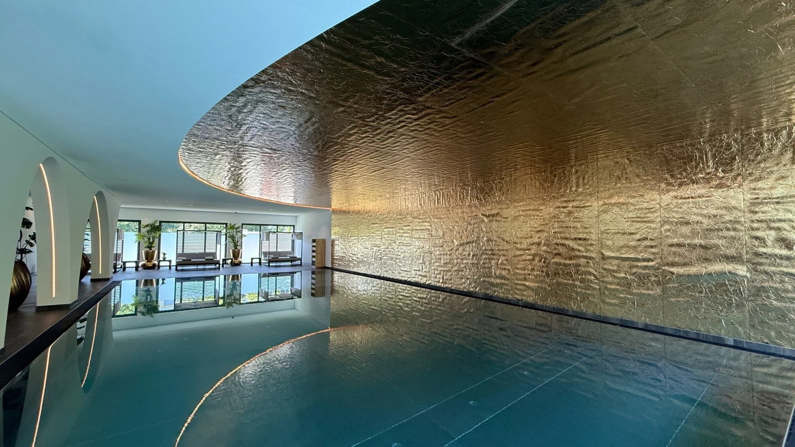 Indoor swimming pool with gold feature wall at BUFF Medical Resort in Konstanz, Germany.