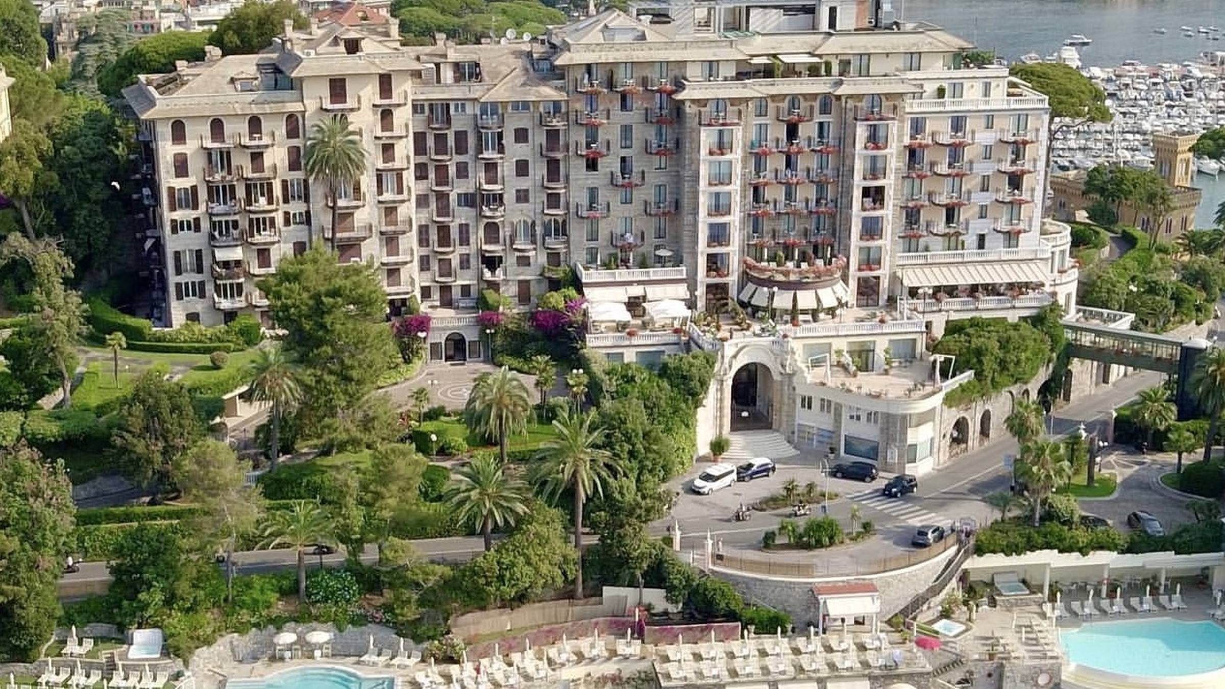 Aerial view of Excelsior Palace Portofino Coast in Rapallo, overlooking the Ligurian Sea with private beach clubs, swimming pools and the Portofino coastline beyond.
