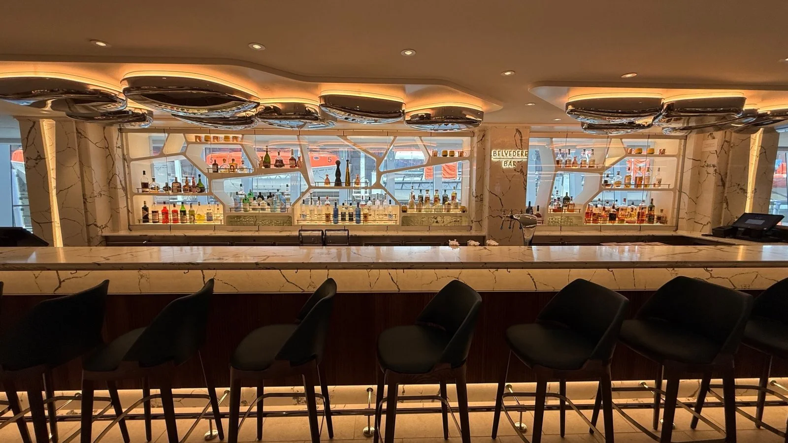 Elegant Belvedere Bar onboard a cruise ship with marble counter, backlit shelves and premium spirits display
