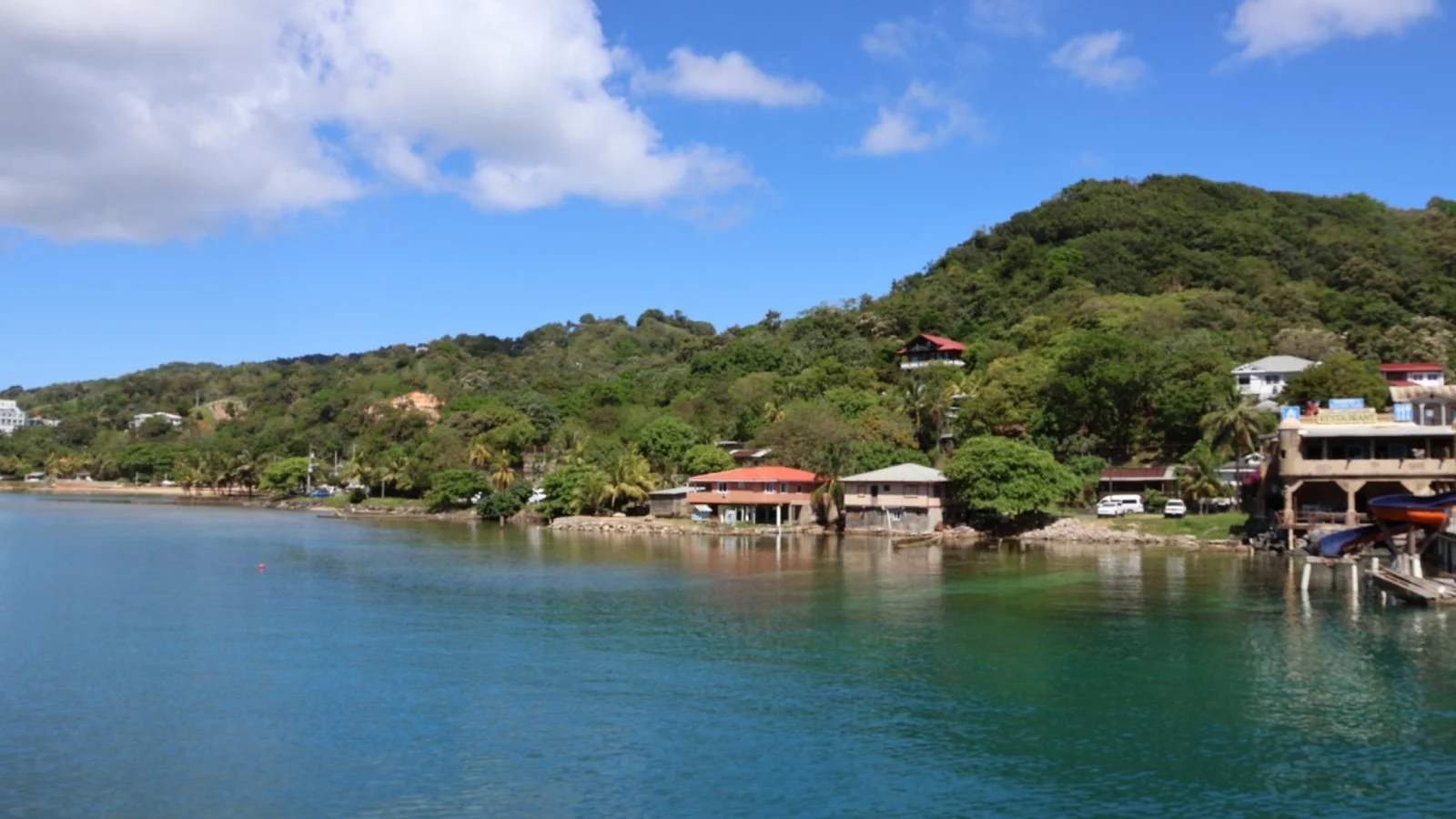 Coastal view of Roatán, Honduras with hillside homes, tropical greenery and calm Caribbean waters