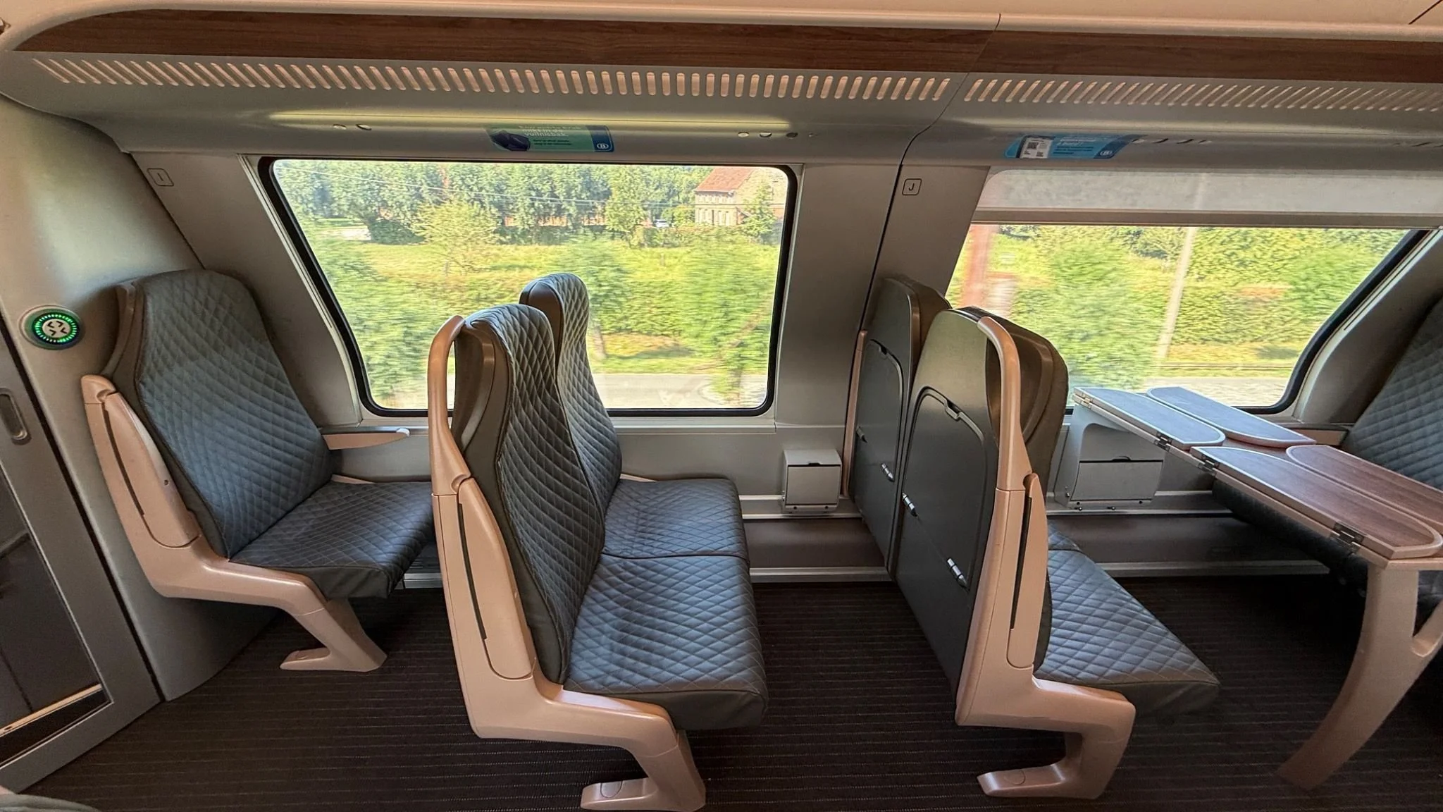 Upper-level First Class seating on a modern Belgian train between Brussels and Bruges.