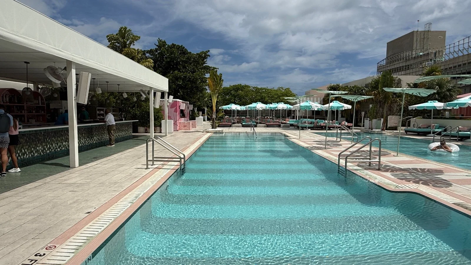 Pool deck at The Goodtime Hotel Miami with pastel umbrellas, outdoor bar and swimming pool