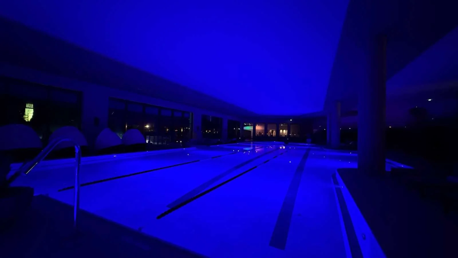 Evening-lit indoor swimming pool at Interalpen-Hotel Tyrol with atmospheric blue lighting