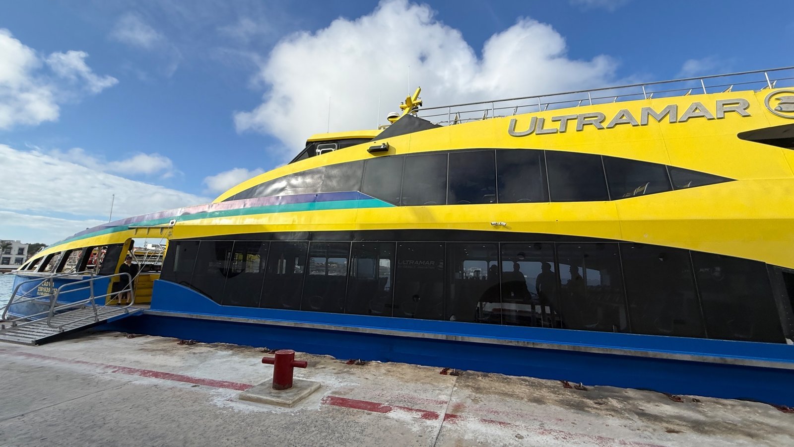Ultramar ferry in Cozumel with yellow exterior and passengers boarding at the dock in Mexico