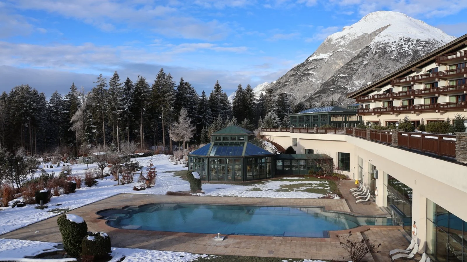 Outdoor pool with snowy Alpine mountain backdrop at Interalpen-Hotel Tyrol