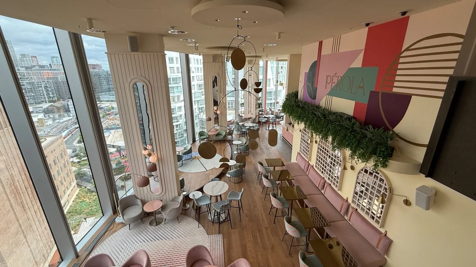 Stylish pastel-toned Perola lounge at art’otel Battersea Power Station with floor-to-ceiling windows, modern seating and elevated views across London.