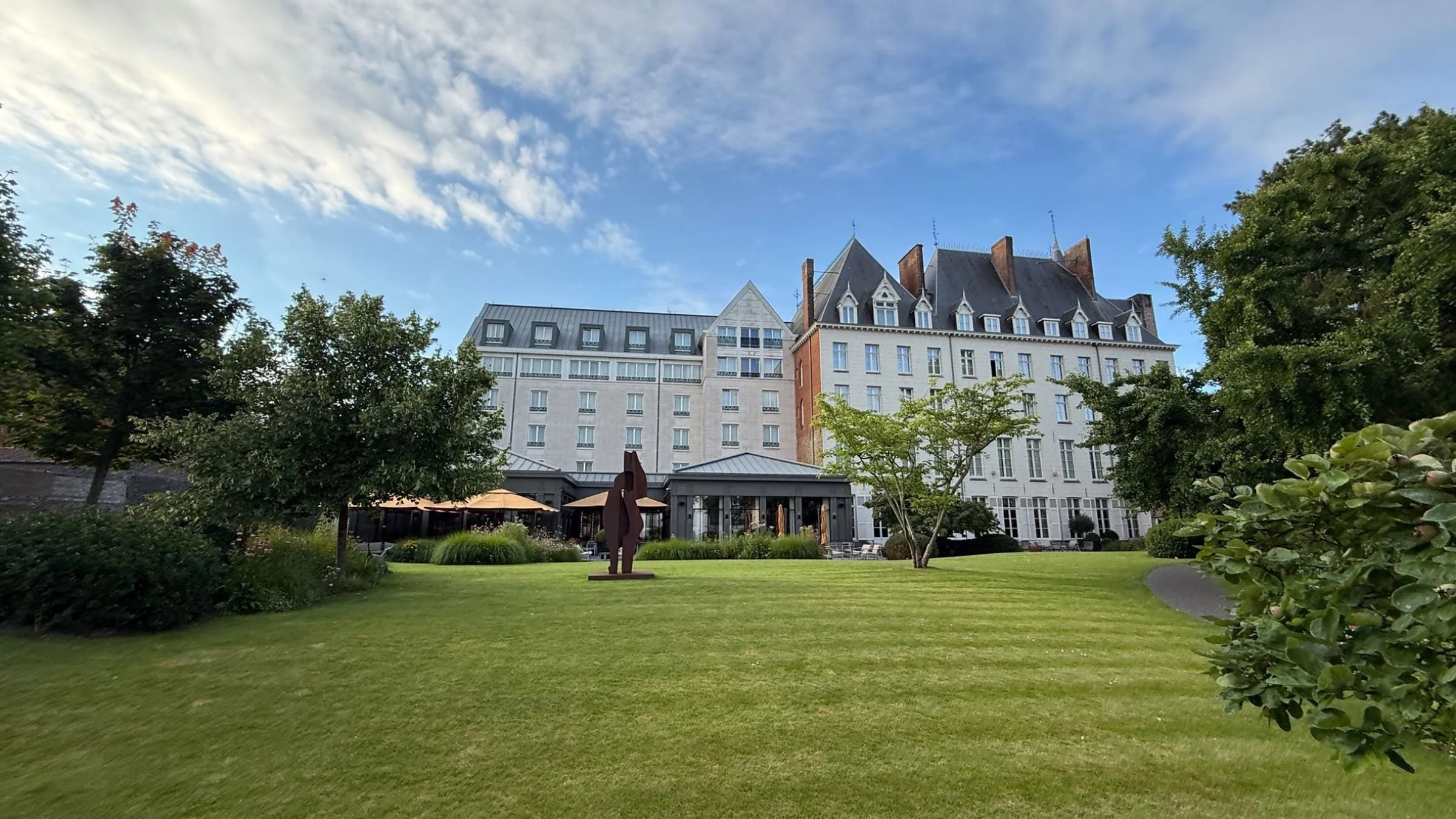 The landscaped gardens and rear façade of Duke's Palace Bruges on a summer evening.