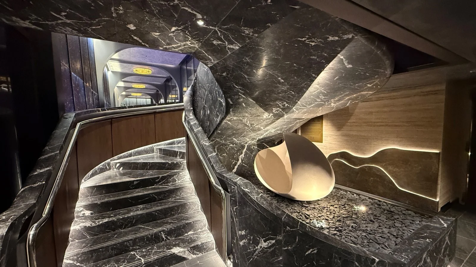 Elegant marble staircase onboard Norwegian Luna with sculptural design and ambient lighting