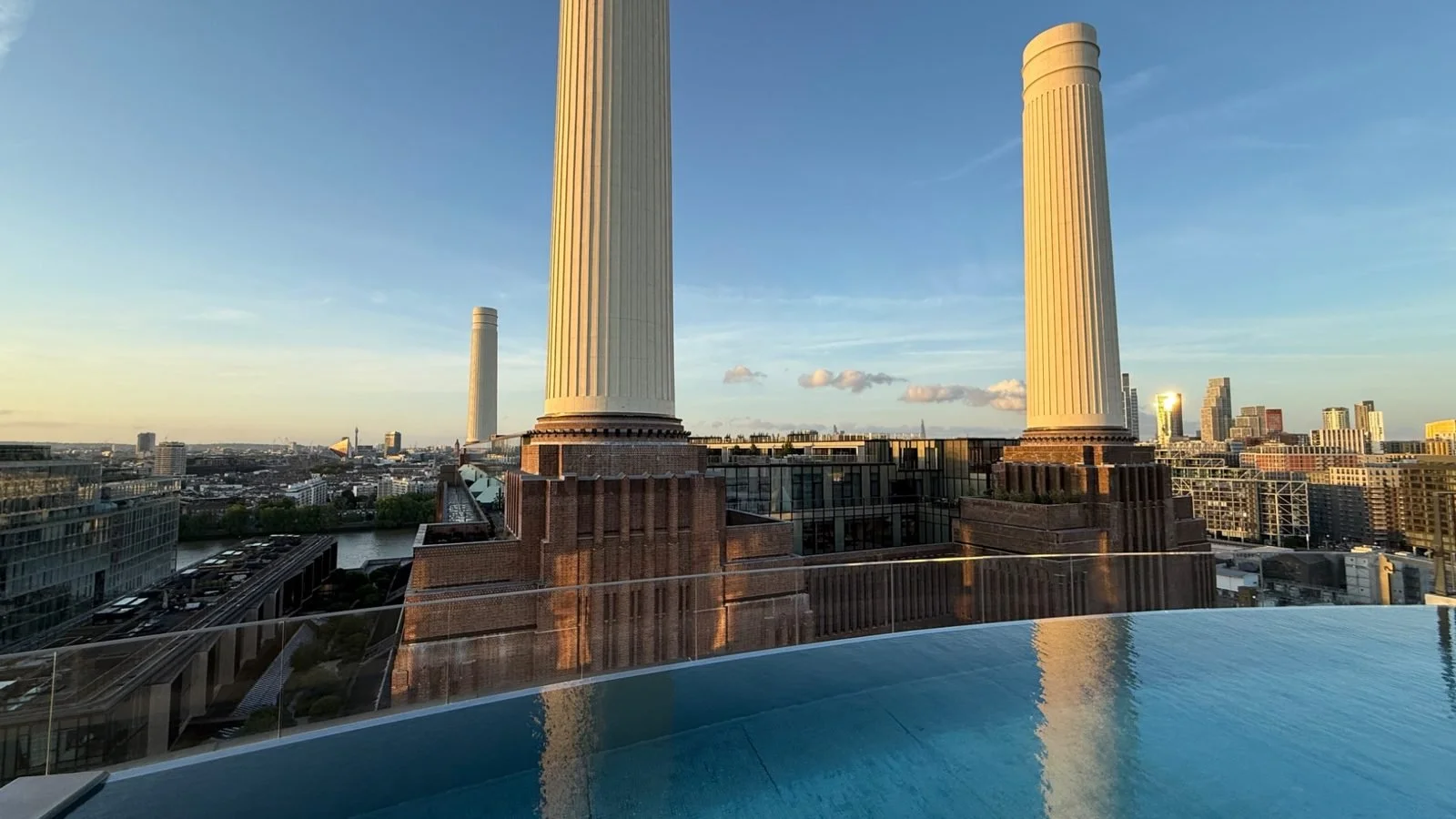 Sunset view across Battersea Power Station chimneys and London skyline from the rooftop infinity pool at art’otel London
