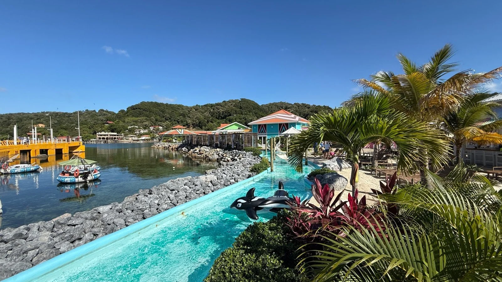 Roatán cruise port area with colourful buildings, palm trees and a tropical water feature overlooking the harbour