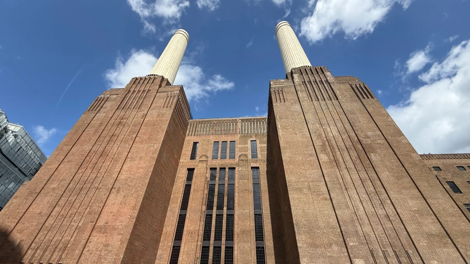 Upward architectural view of Battersea Power Station’s famous twin chimneys and Art Deco brickwork in London