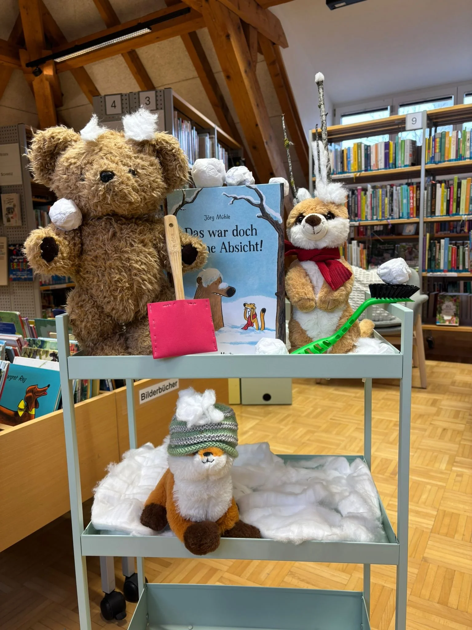 Verzierte Buchhandlung mit Stofftieren, Winterdekoration, einem Buch und anderen Büchern im Hintergrund.