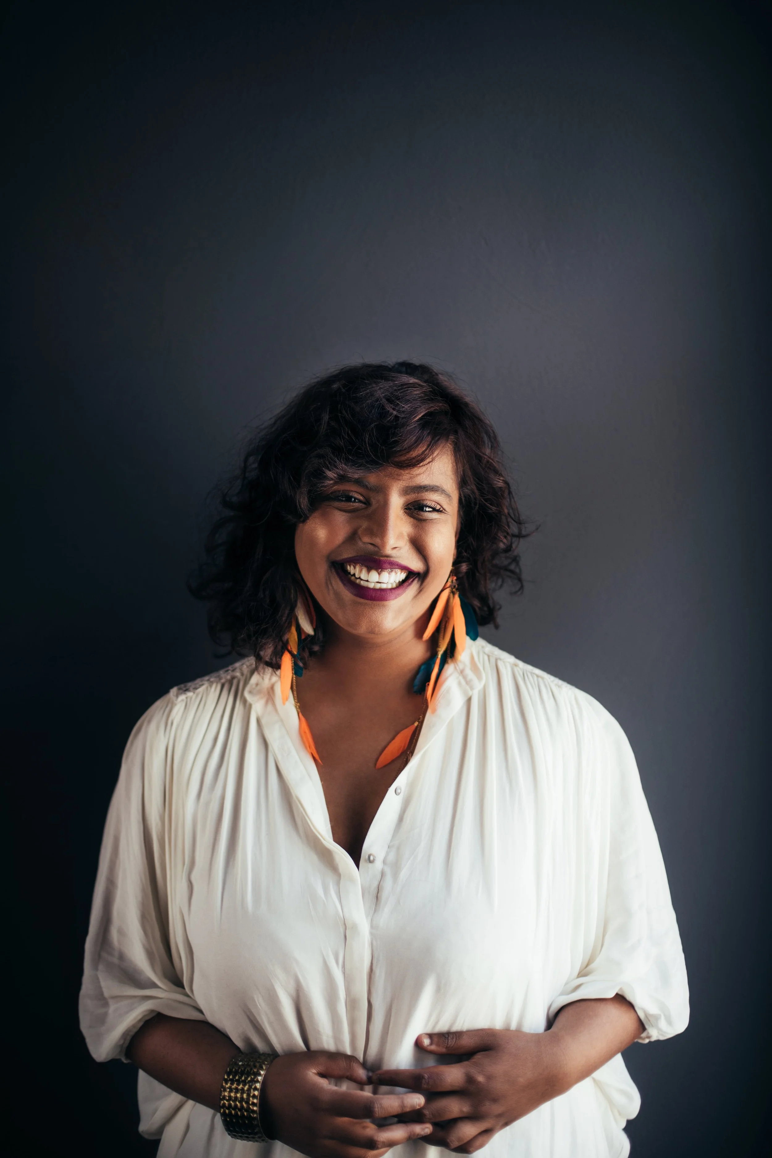 Retrato de uma mulher indiana sorridente tirado contra uma parede escura