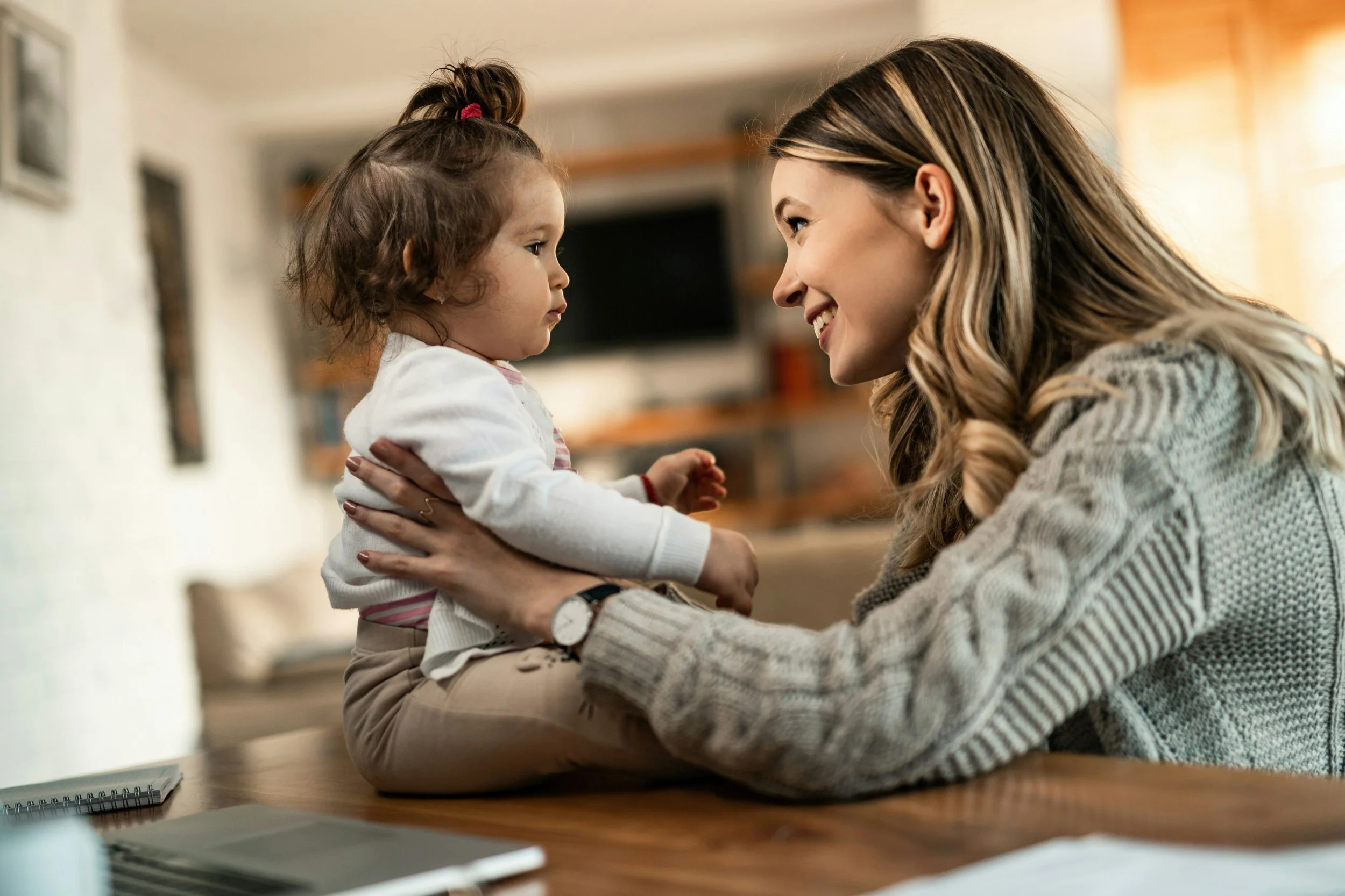 Baby engaging in play and early communication with a parent to support speech and language development in the first years of life.