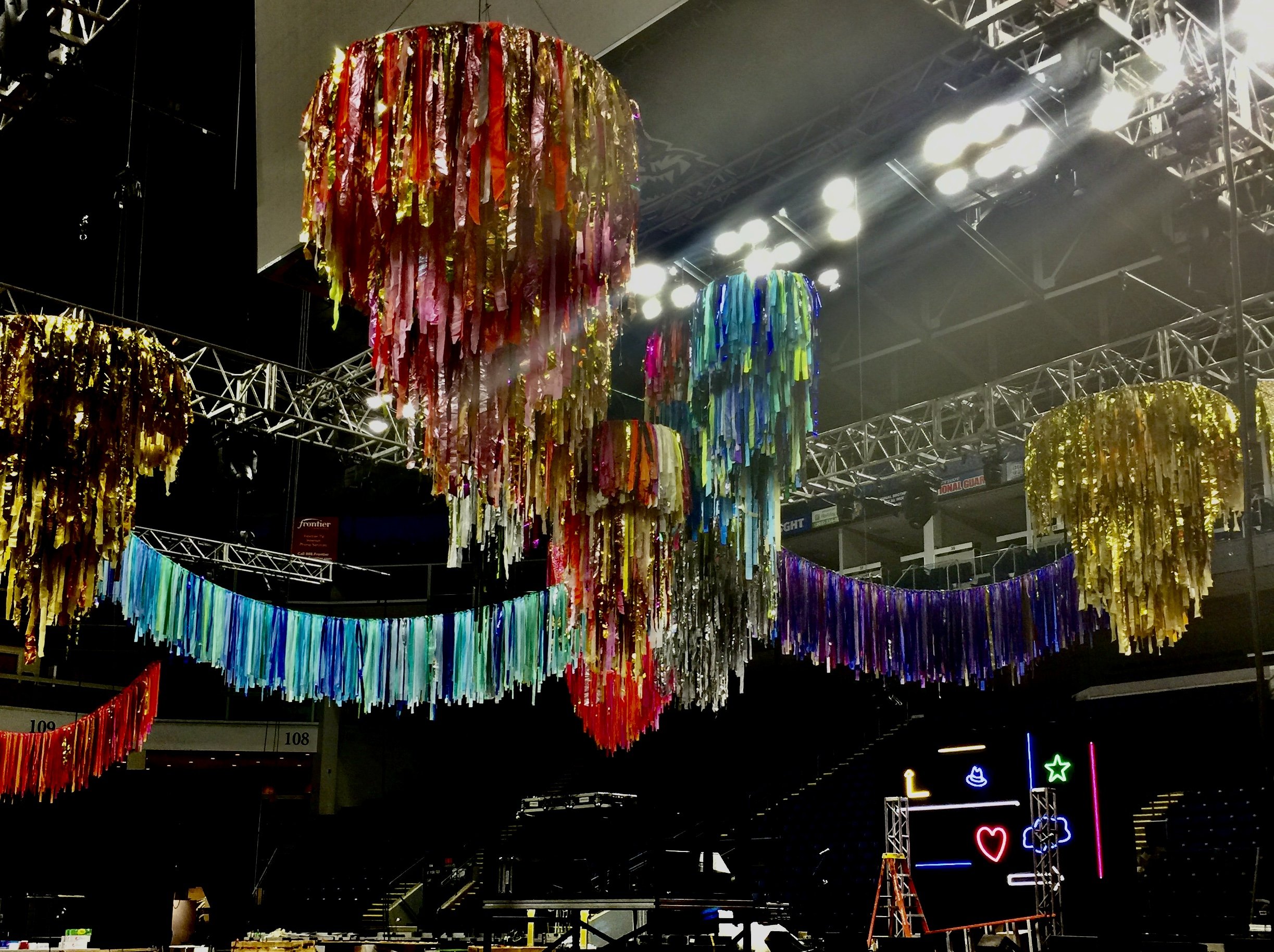 Colorful hanging decorations with ribbons in a dark indoor venue, possibly for an event or celebration.