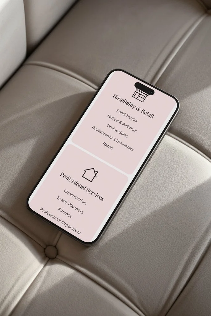 Smartphone displaying a menu with categories for 'Hospitality & Retail' and 'Professional Services' placed on a beige leather seat.