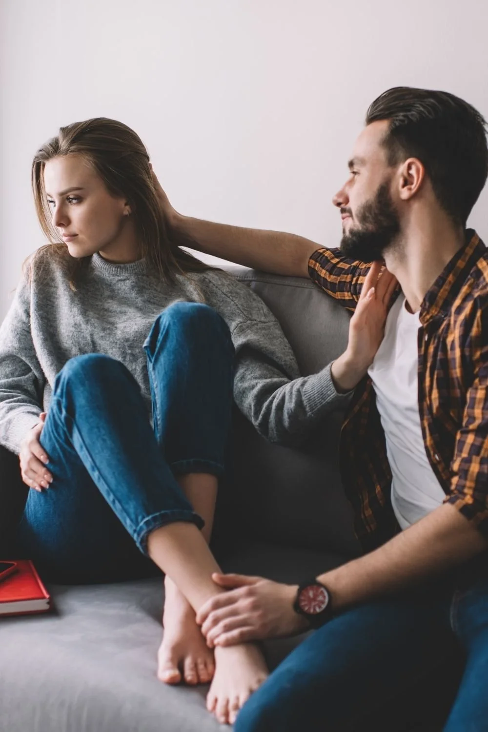 Young woman sitting on the couch pushing her partner away
