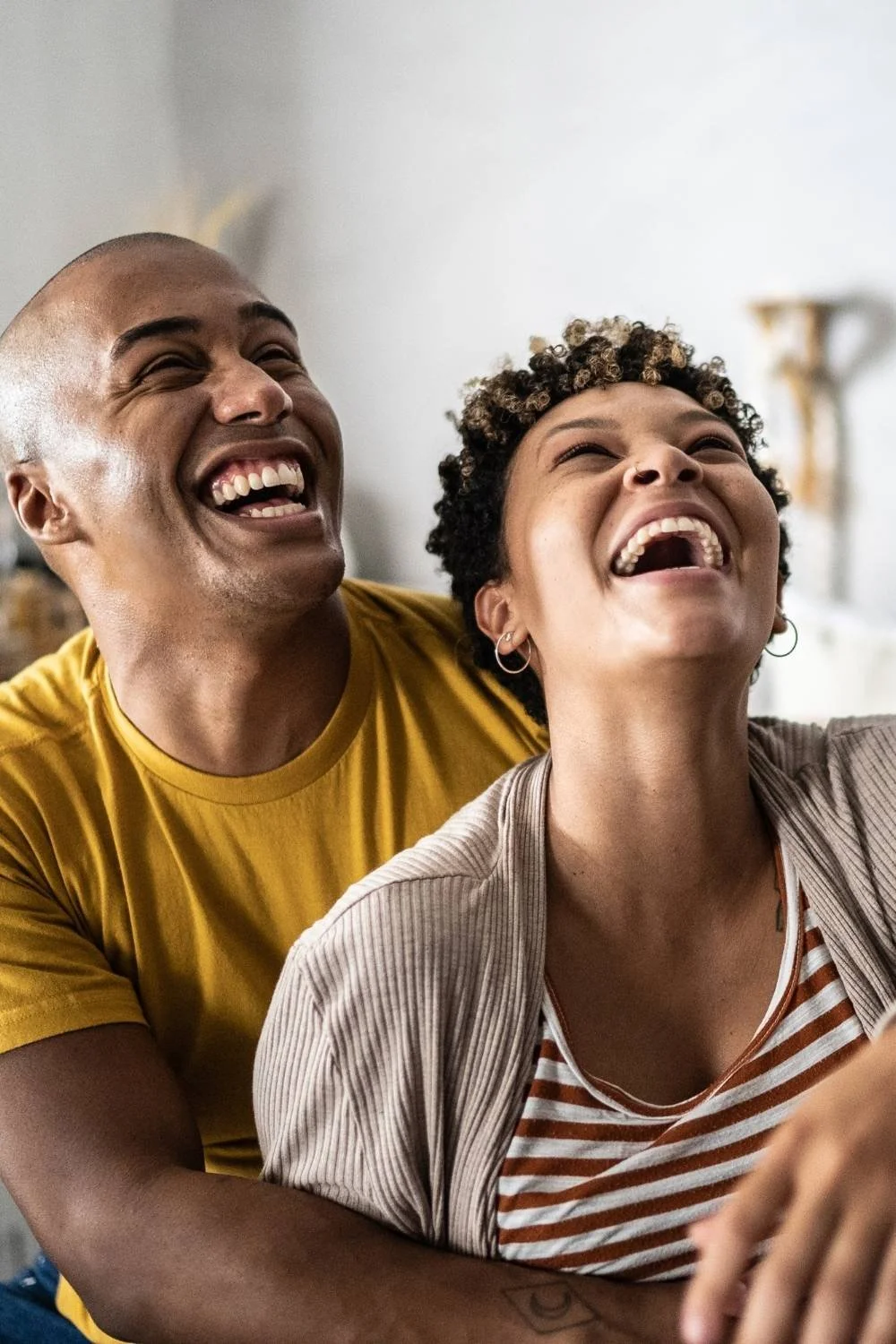 Young couple laughing with each other in the bedroom