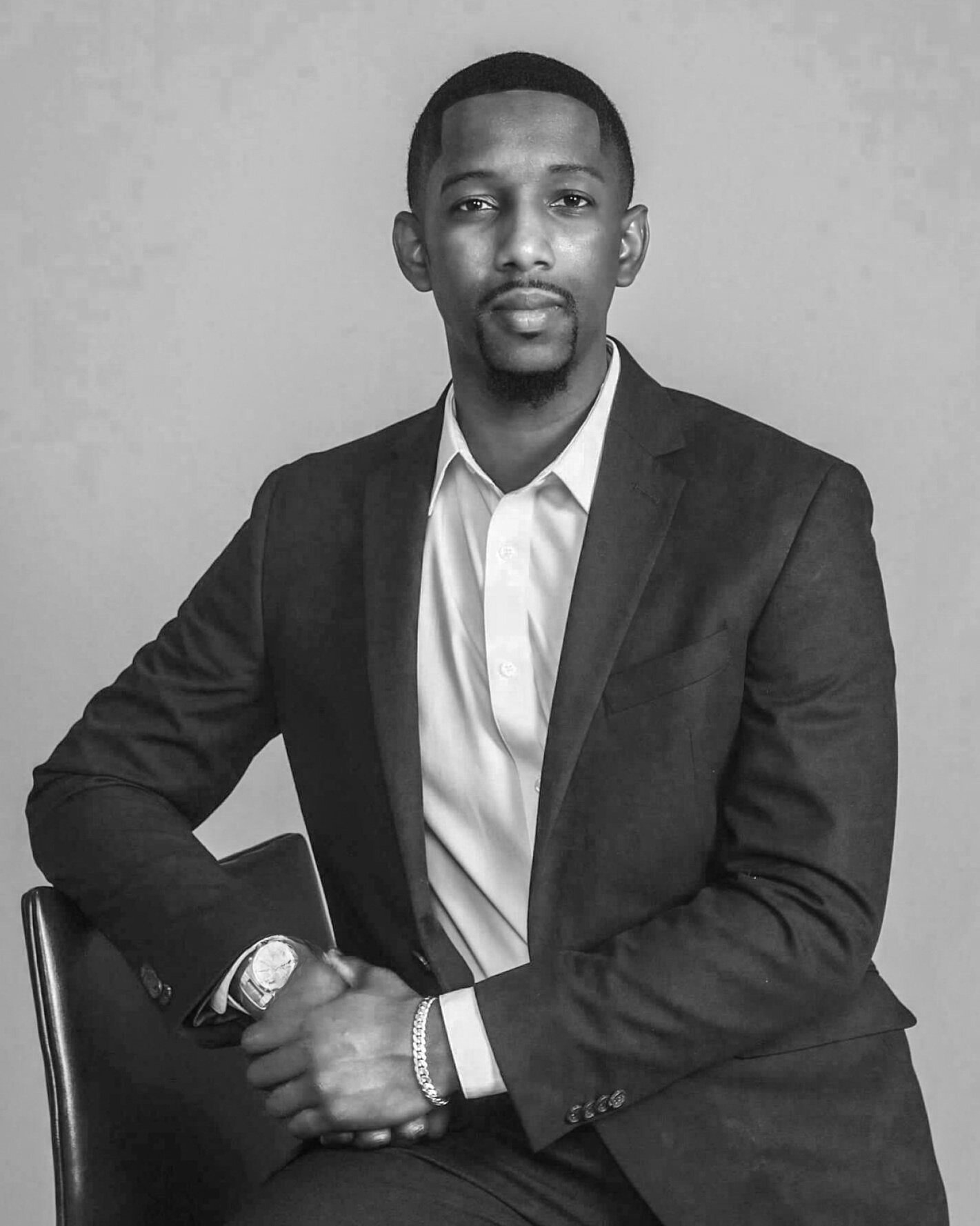 Pastor WJ Daggins in a suit and white shirt, seated and looking at the camera. Black and white portrait.